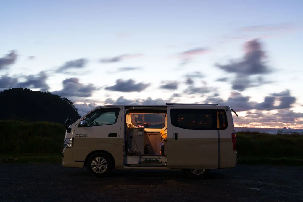 A campervan parked by the beach at dawn