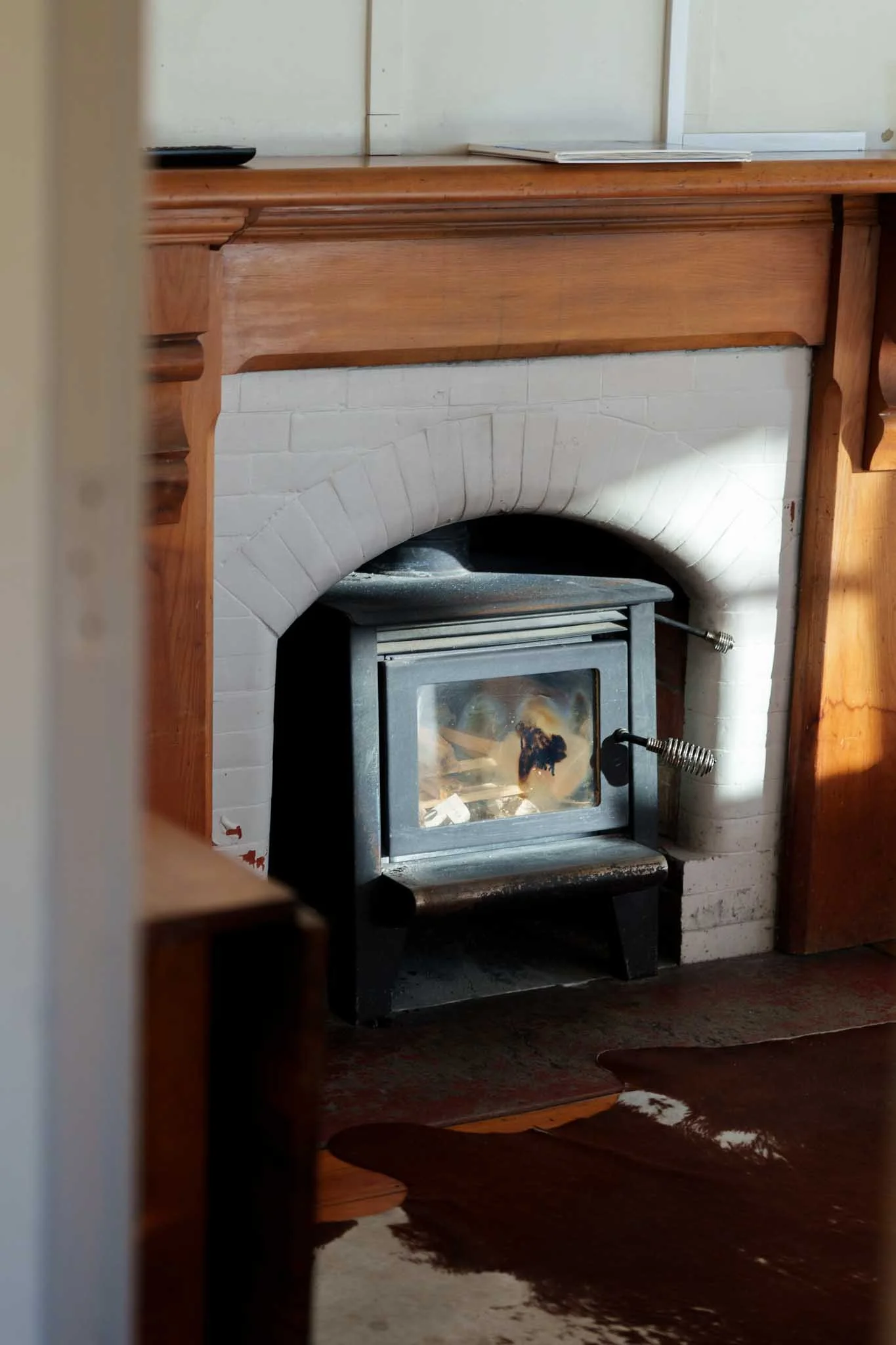 A cowhide lies on the floor in front of a log fireplace in Tekapo