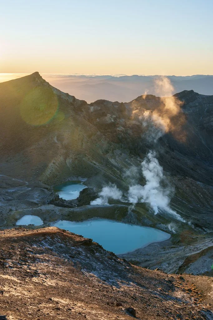 Early morning sunlight illuminates the steam rising around the Emerald Lakes on the Tongariro Crossing