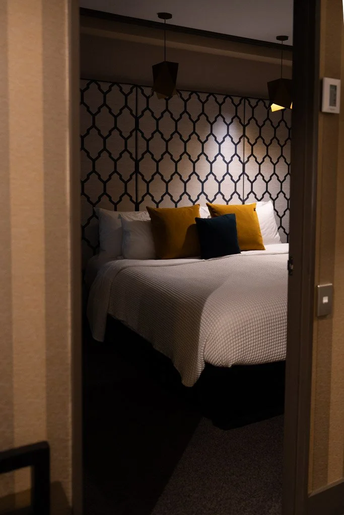 A bedroom with gold and navy cushions on the bed at a hotel in Wellington