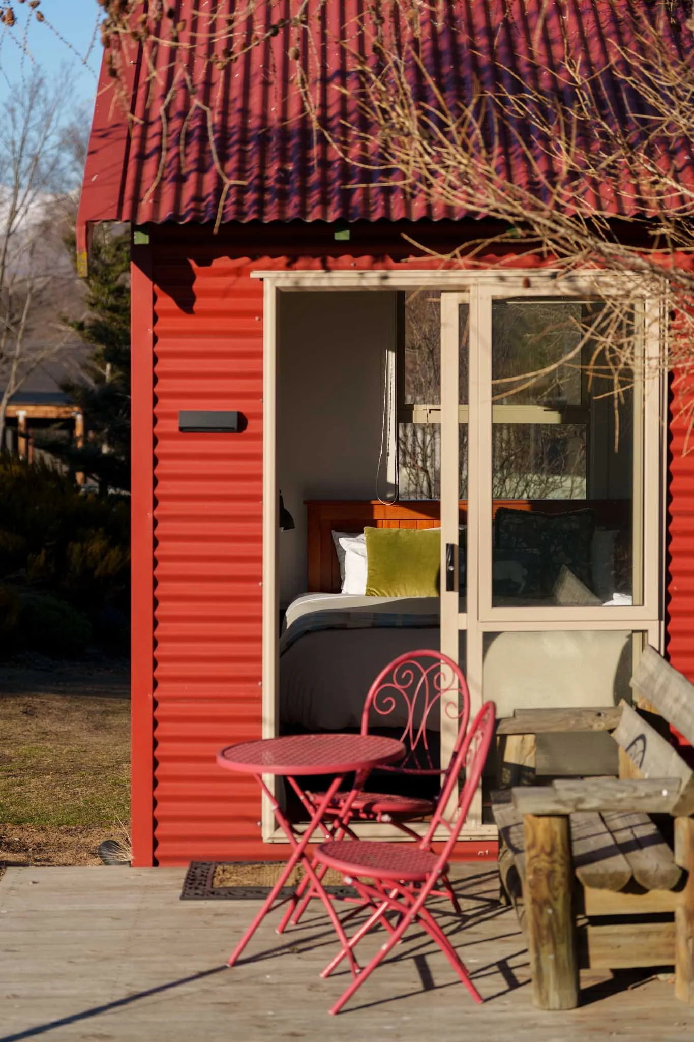 A table and chairs sit outside a studio room flooded with sunlight in Tekapo