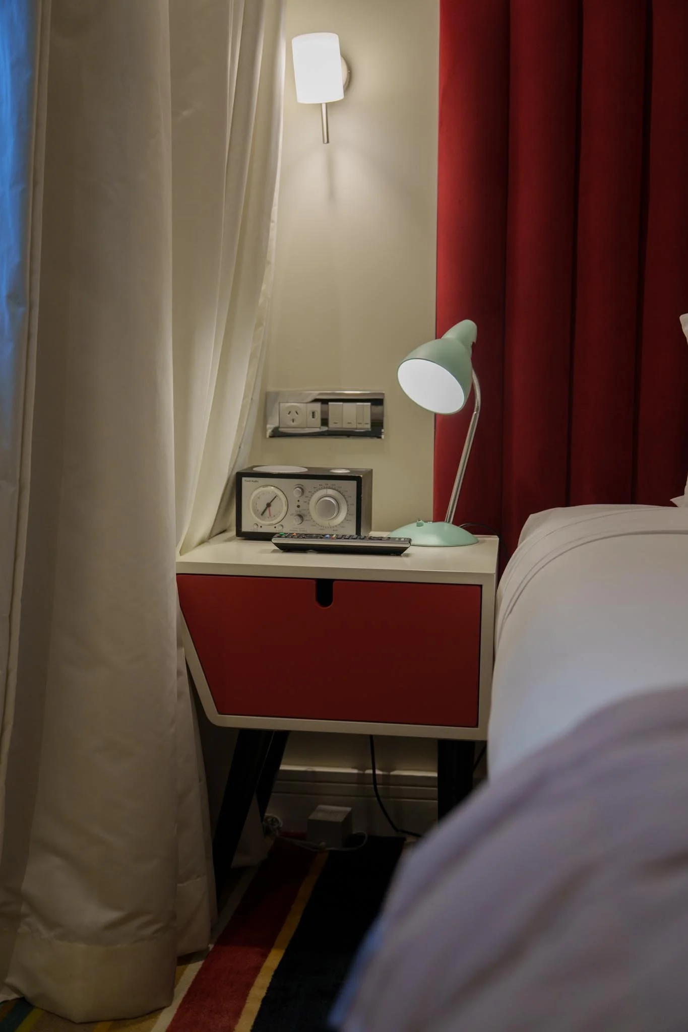 A lamp sits on a bedside table next to a hotel room bed