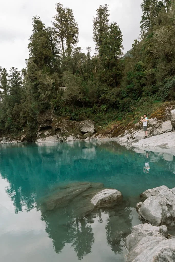 Trees are reflected in the bright blue surface of Hokitika Gorge