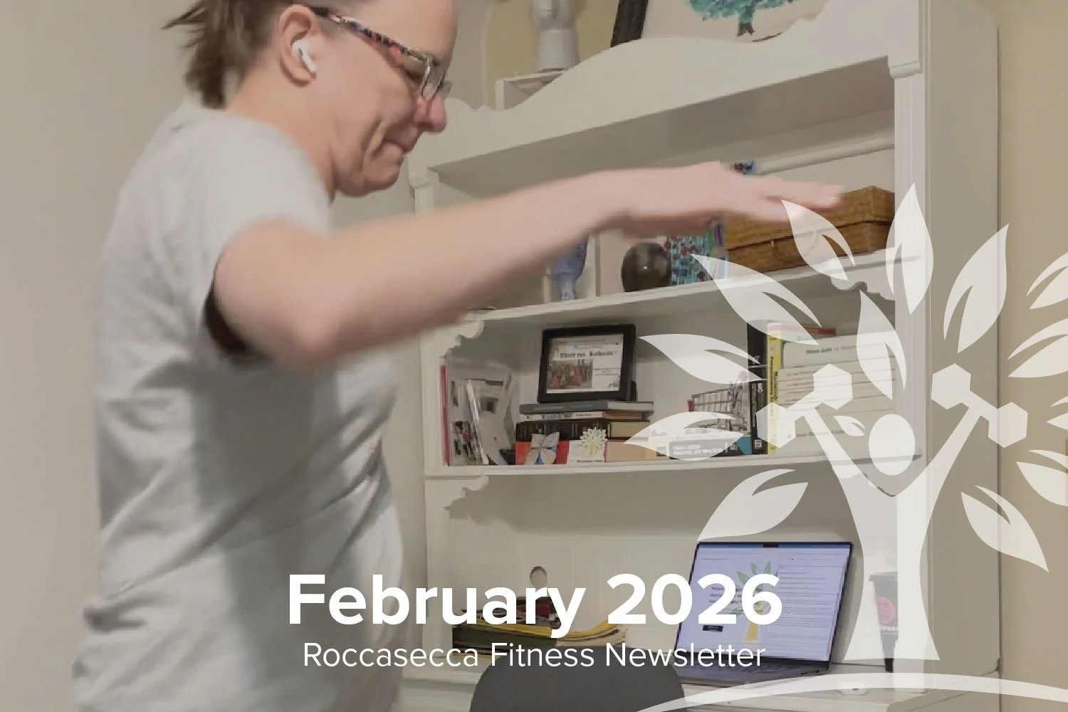 A woman with short blonde hair, glasses, and white earbuds, stretching in a home office, with a white desk, laptop, and a white shelf filled with books and decorative items in the background.