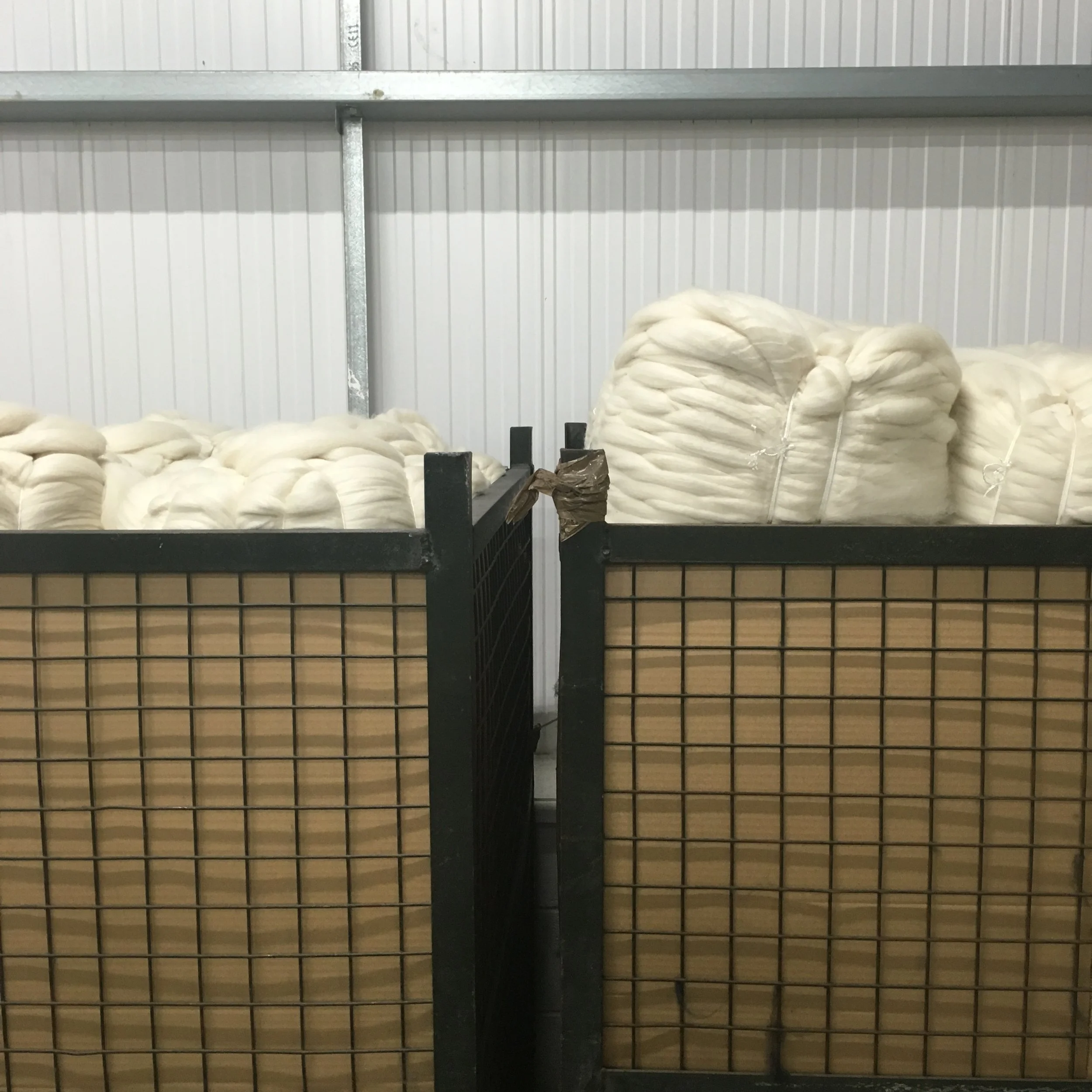 Two large industrial bins filled with white cotton-like material in a storage facility.