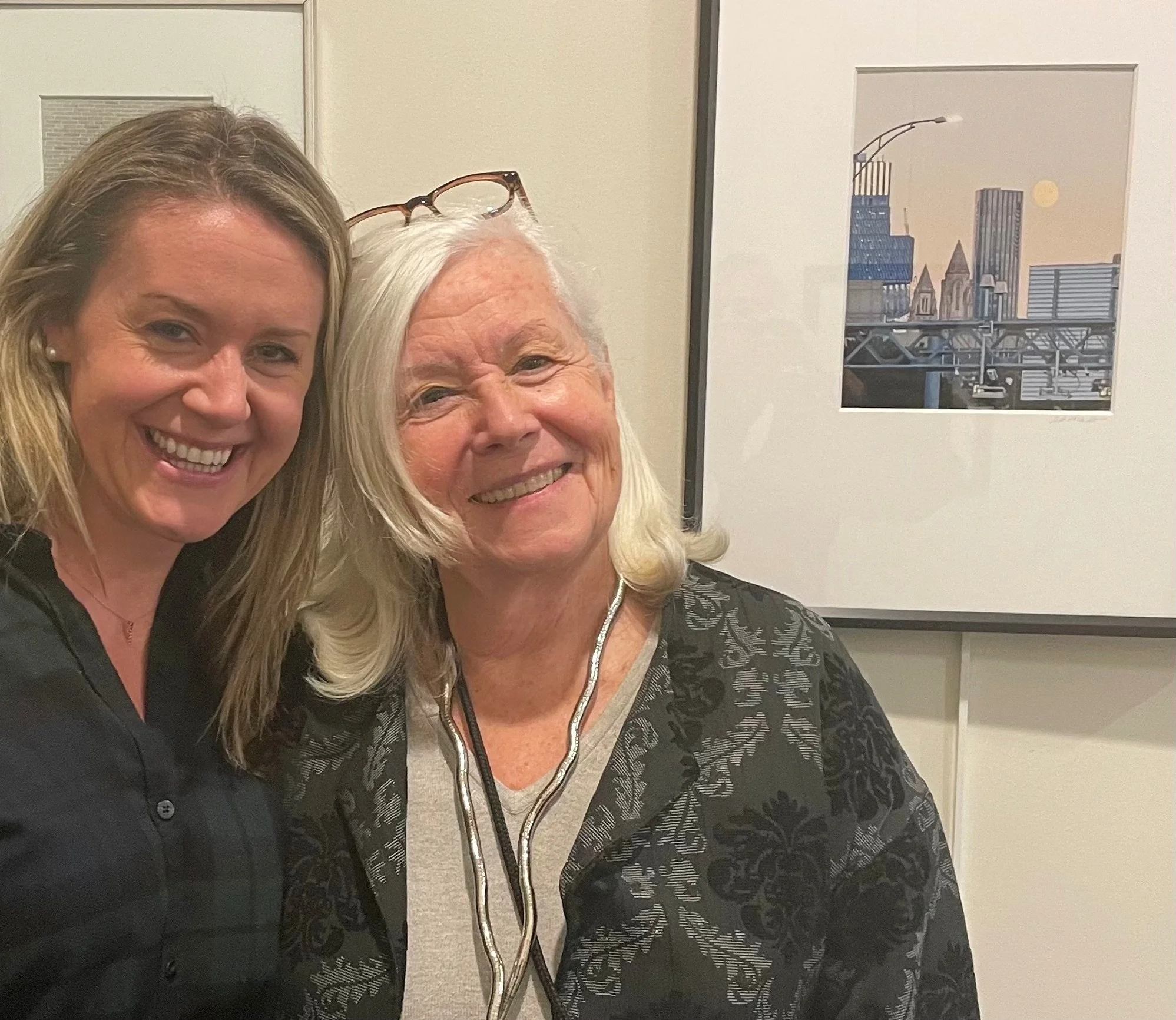 Barbara with her niece in front of Barbara's photo of a Boston cityscape
