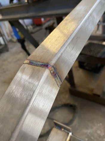 Metal bar with a weld joint in a workshop setting.