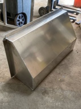 A large metal funnel-shaped object on the ground in a workshop.