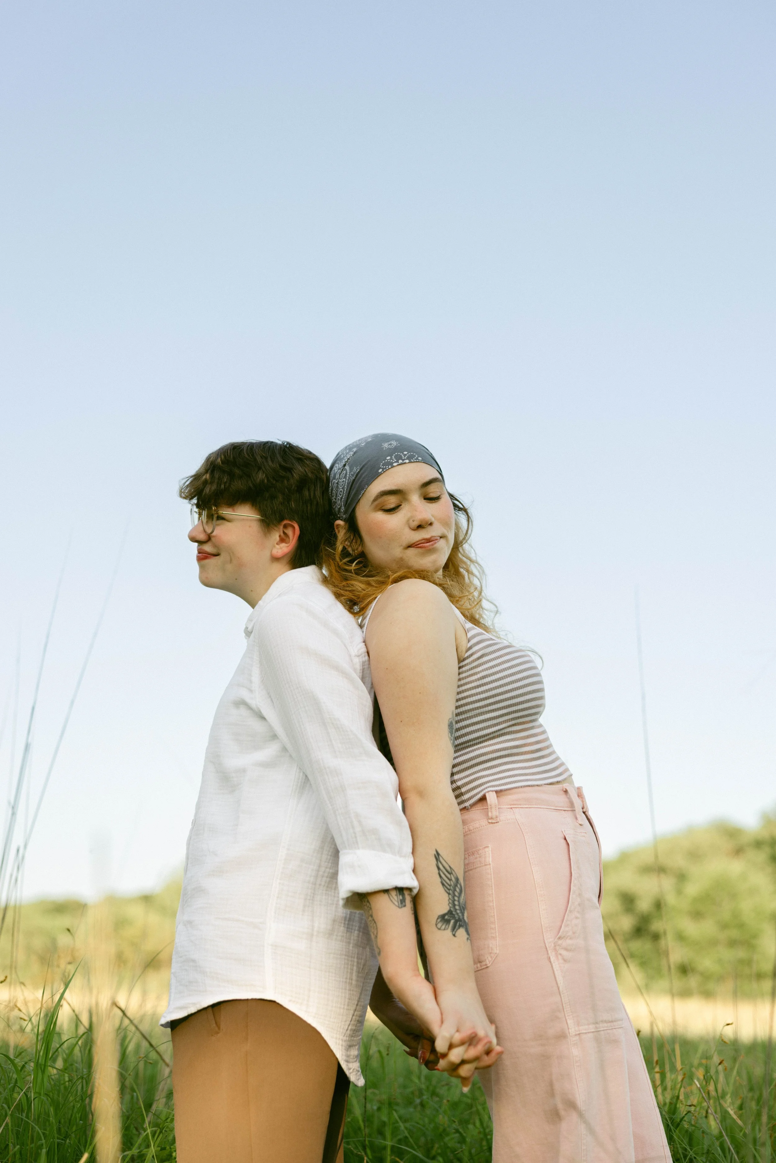 Lesbian couple snuggles in tall prairie grass during their surprise proposal in Ames, Iowa