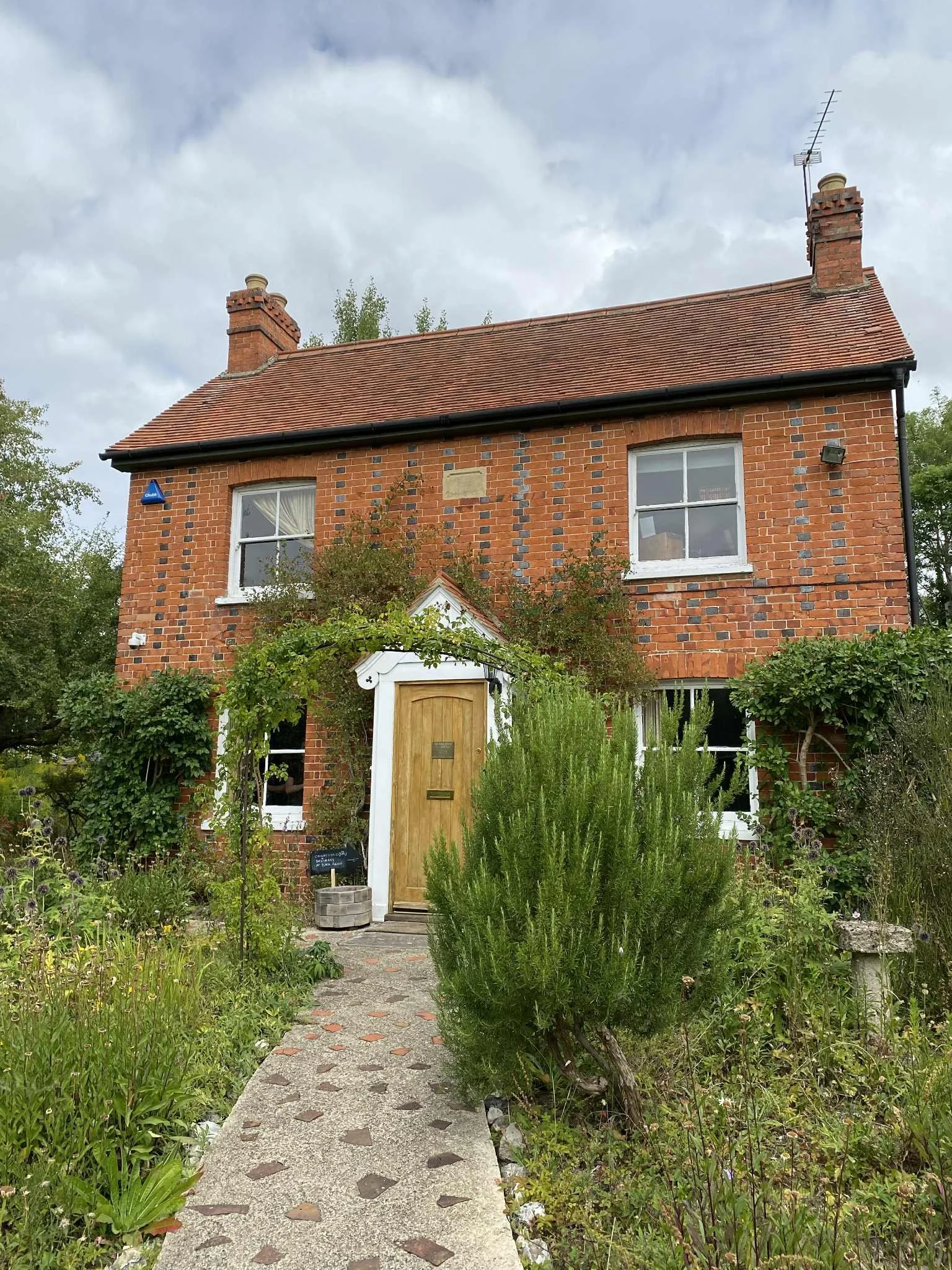 A red brick house surrounded by a cottage garden known as The Bach Centre in England