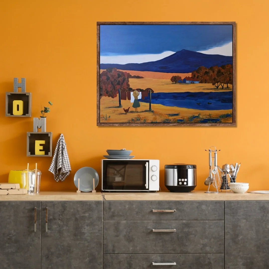 A bright kitchen with grey cabinets, an orange wall, and the Silence of the Land framed abstract artwork painting above the counter.