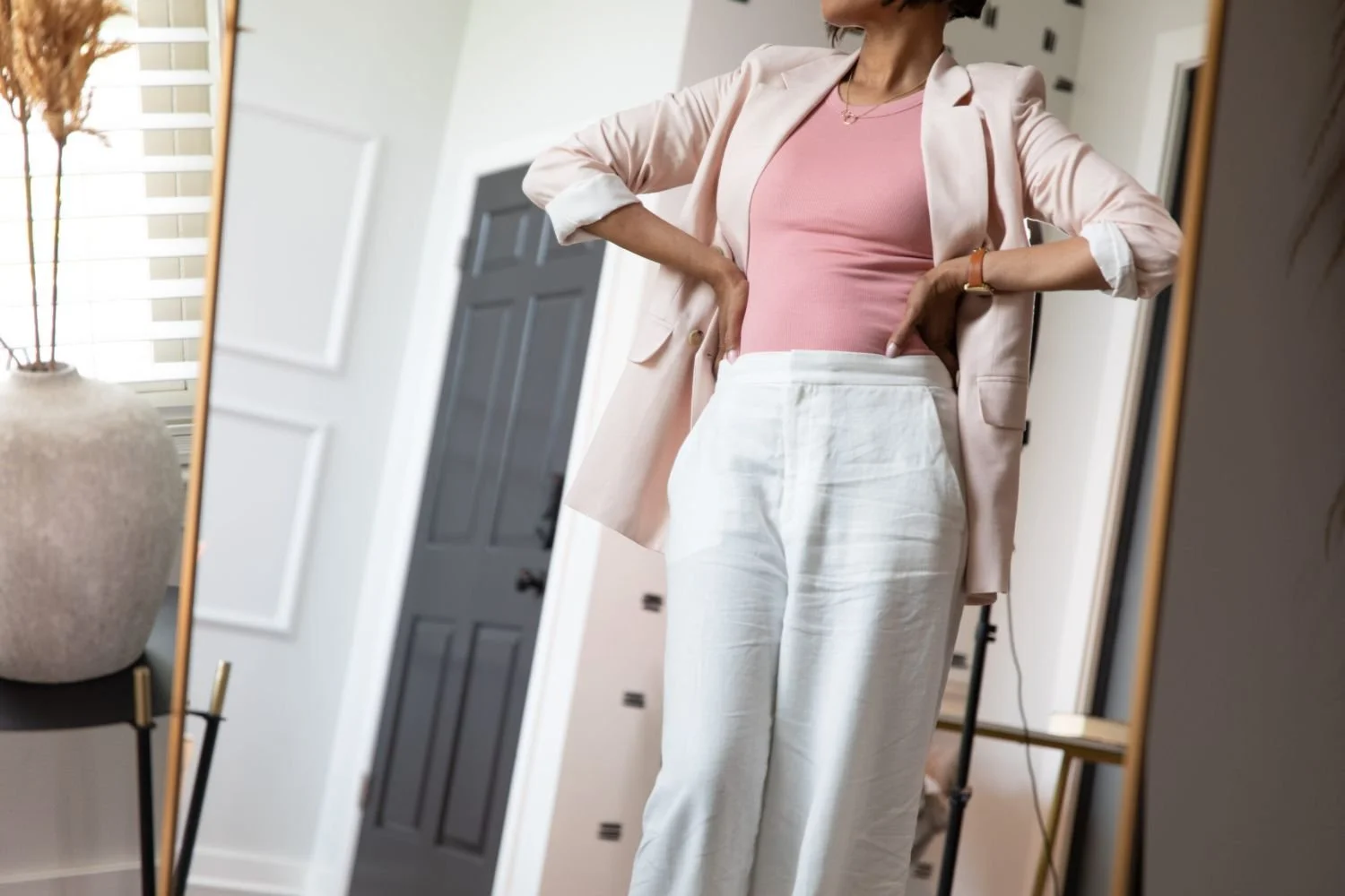 Black woman standing confidently in front of a mirror, reflecting growth and breaking generational patterns