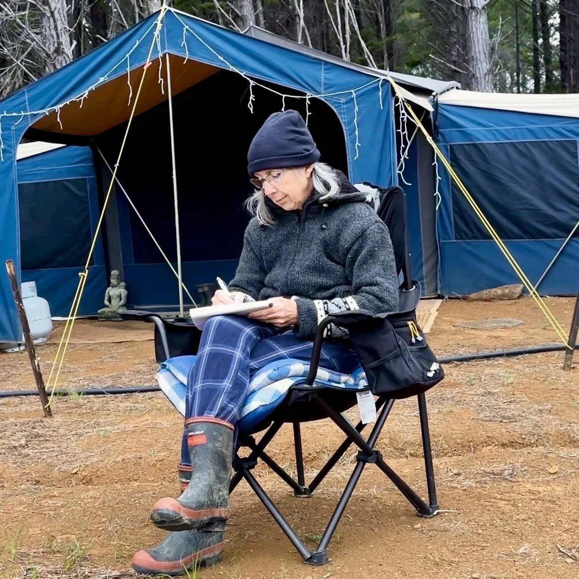 Woman writing in a journal outside a tent