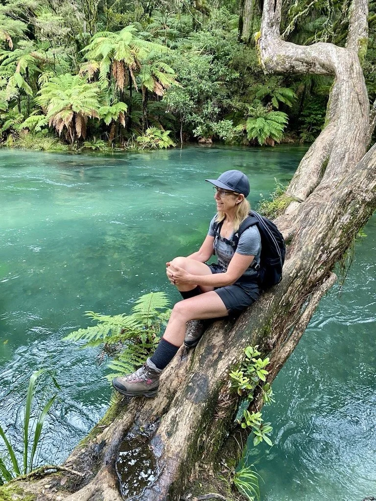 Hiker pausing by the Tarawera River along the walking track