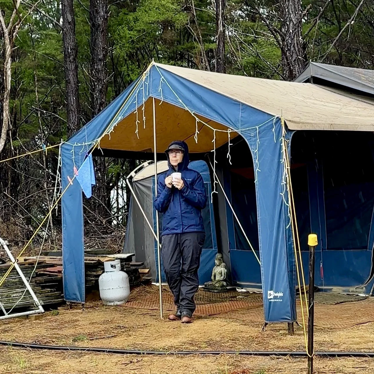 Sharon standing outside of tent dressed in wet weather clothes