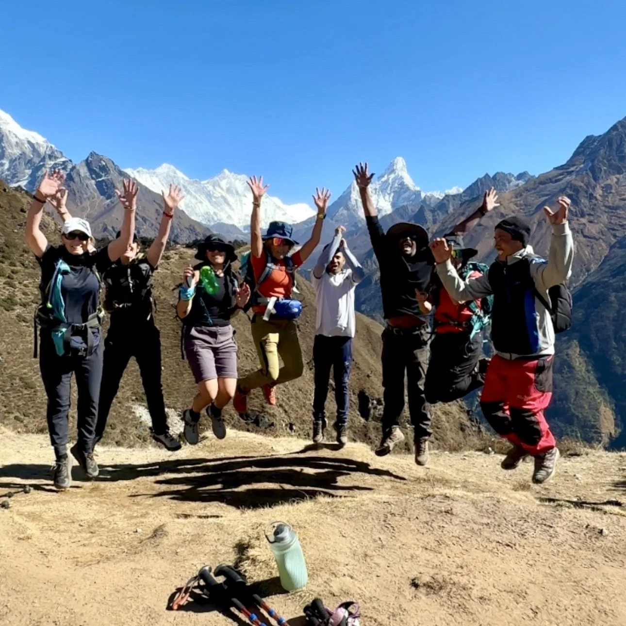 Excited Everest Base Camp trekkers jumping for joy in front of Himalayan mountains