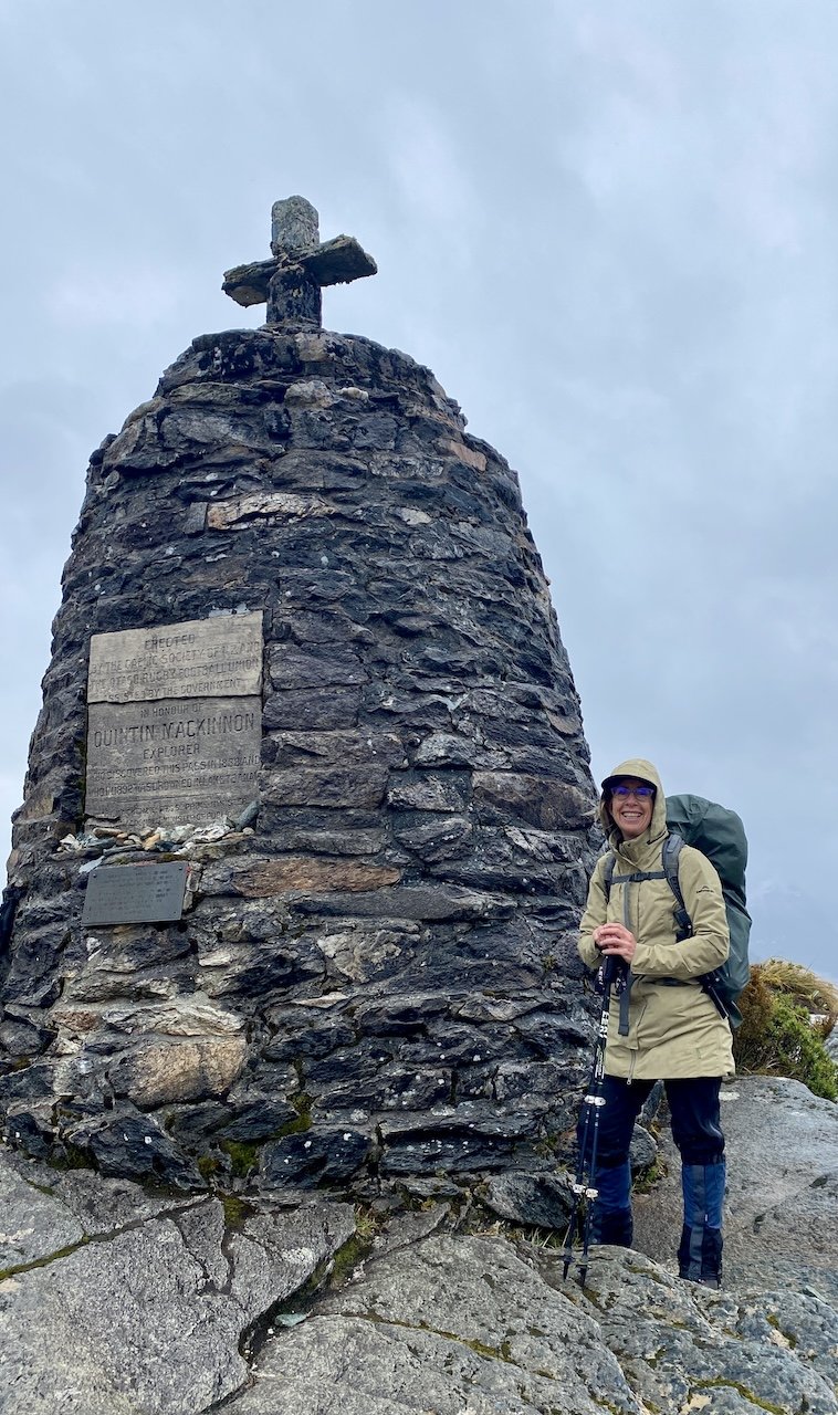 Sharon Evans beside the MacKinnon Pass Memorial, Milford Track, Fiordland National Park, New Zealand Great Walks
