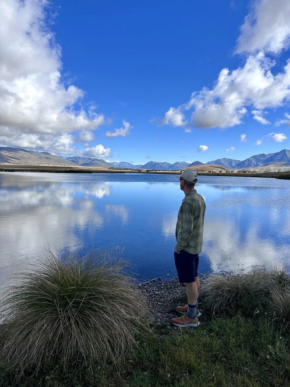 Person practising self awareness by reflecting at a lake at sunrise
