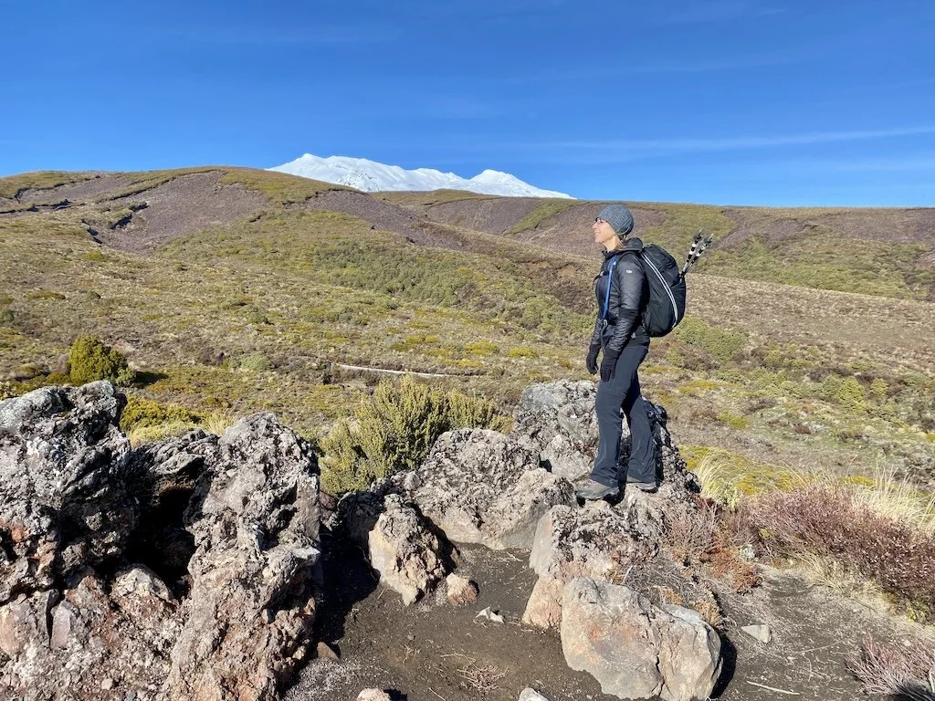 Hiker dressed in layered clothing including jacket, fleece, and hat on exposed mountain trail