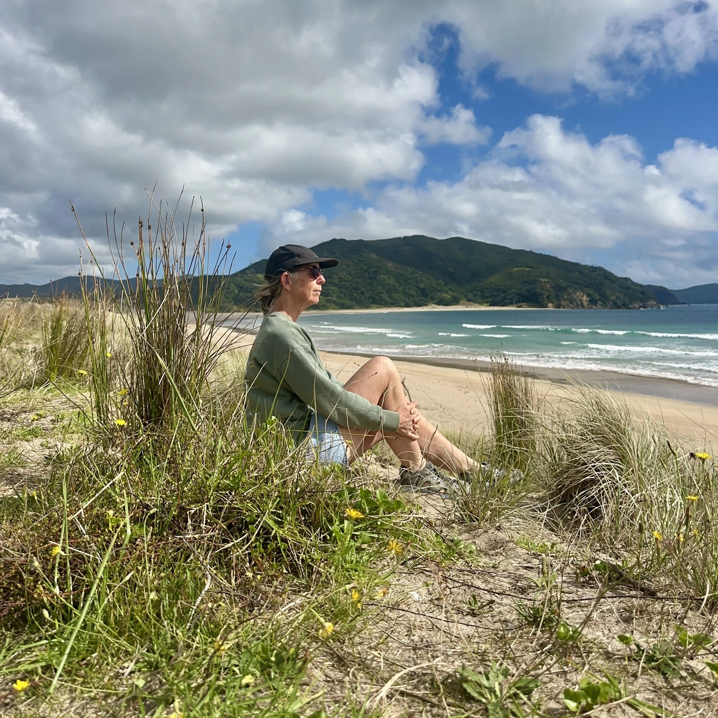 Woman reflecting while sitting amongst sand dunes