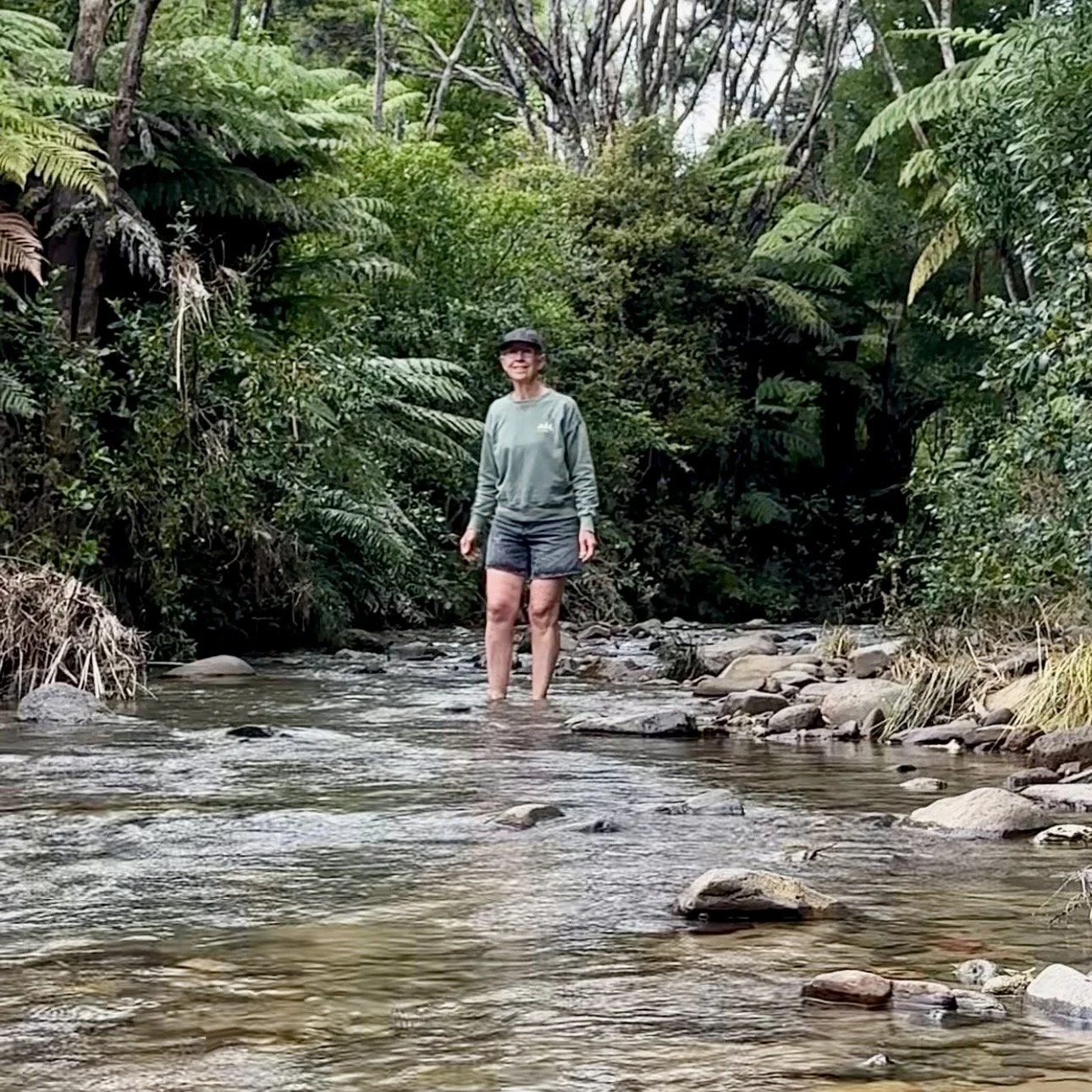 Lady walking in shallow  stream surrounded by New Zealand native forest