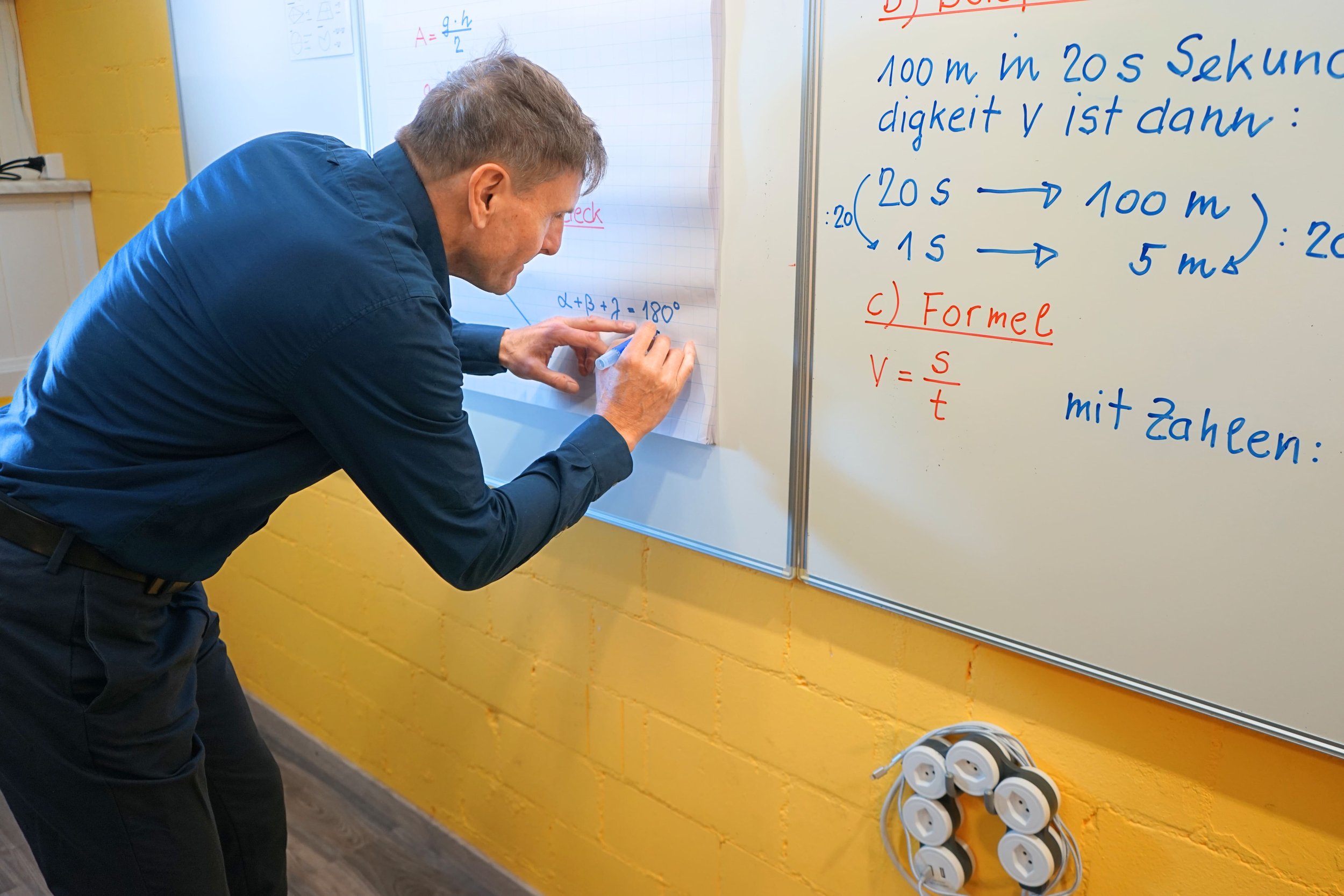 Der Lernhelfer Marcus Cavegn steht an der Tafel und löst eine Mathe-Aufgabe.