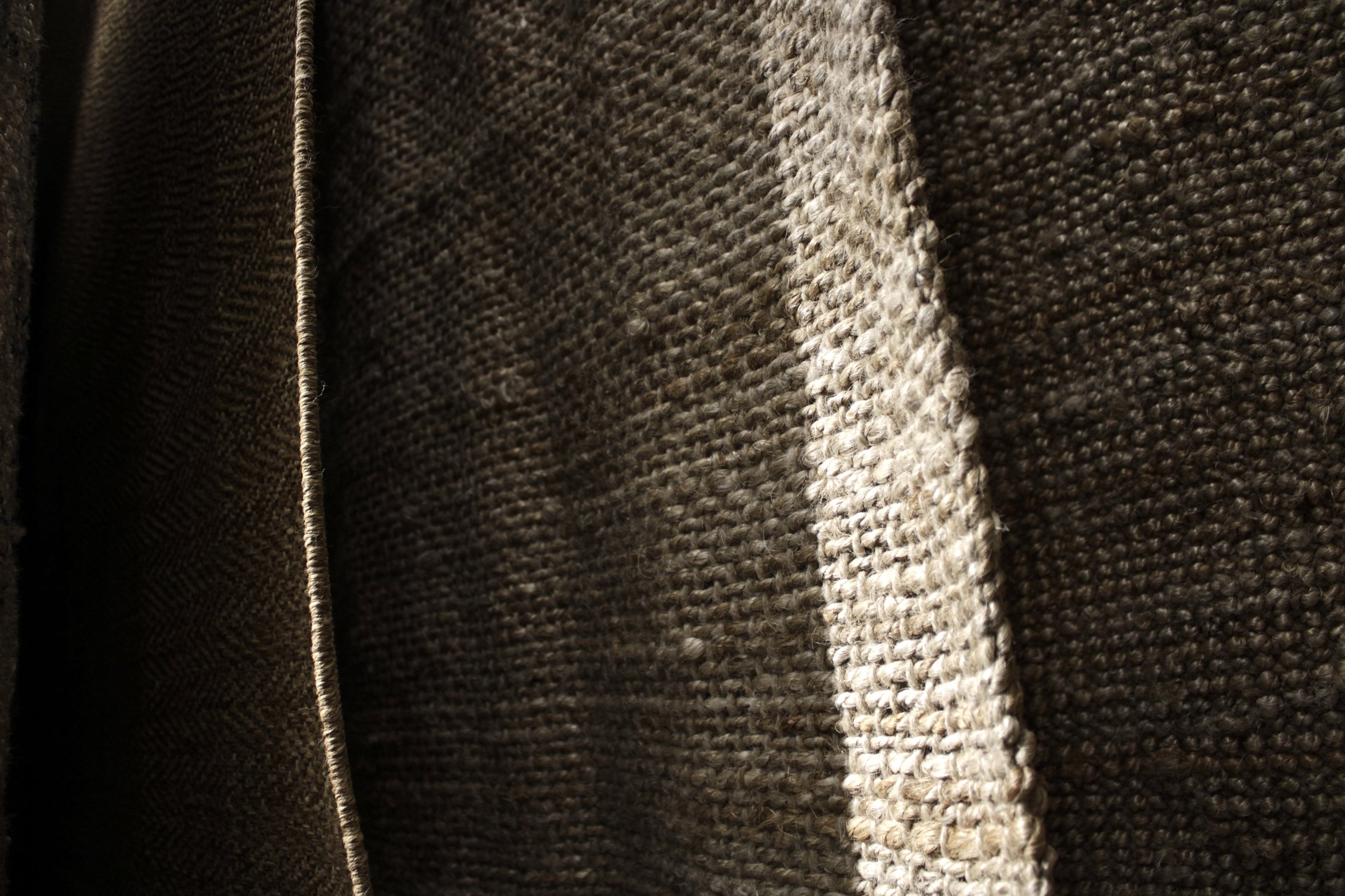 Hanging rugs shot up close from the side so that the space between them is visible.