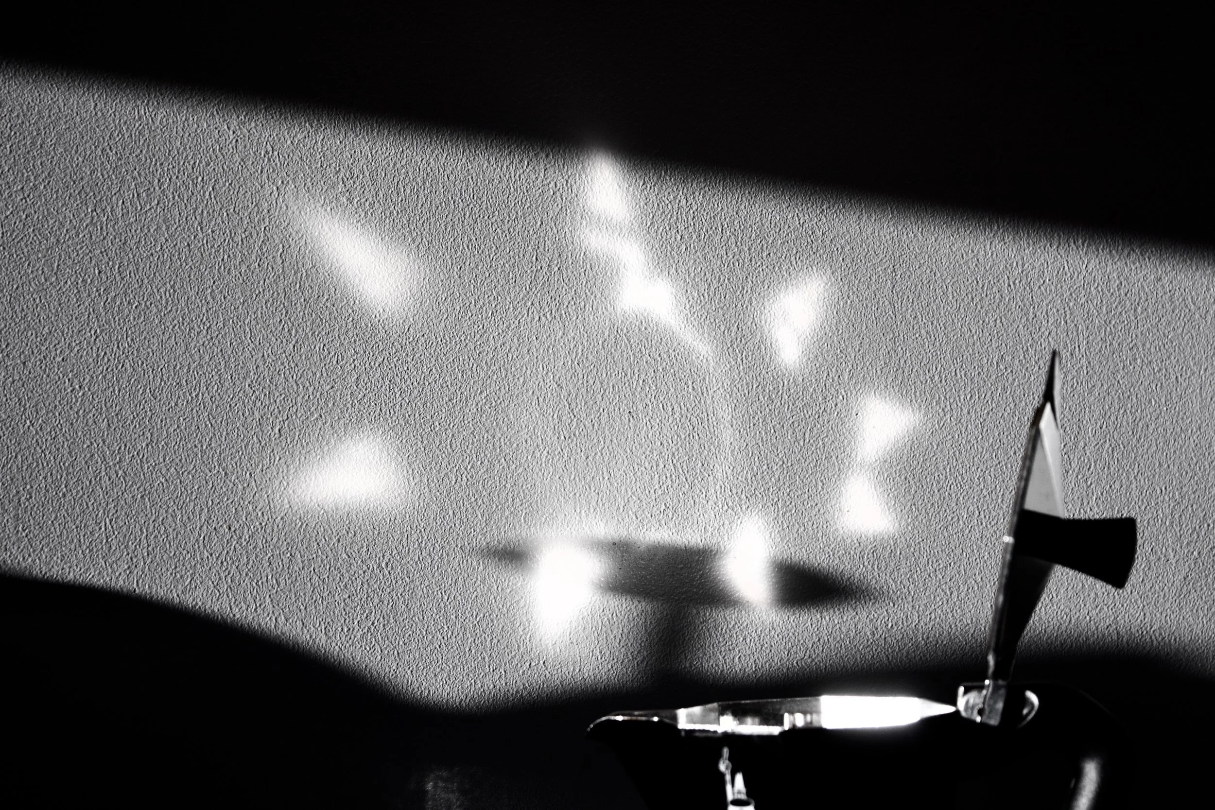 Close-up of a metal object with a textured surface, reflected in a shiny surface, with bright spotlights creating a starburst pattern.
