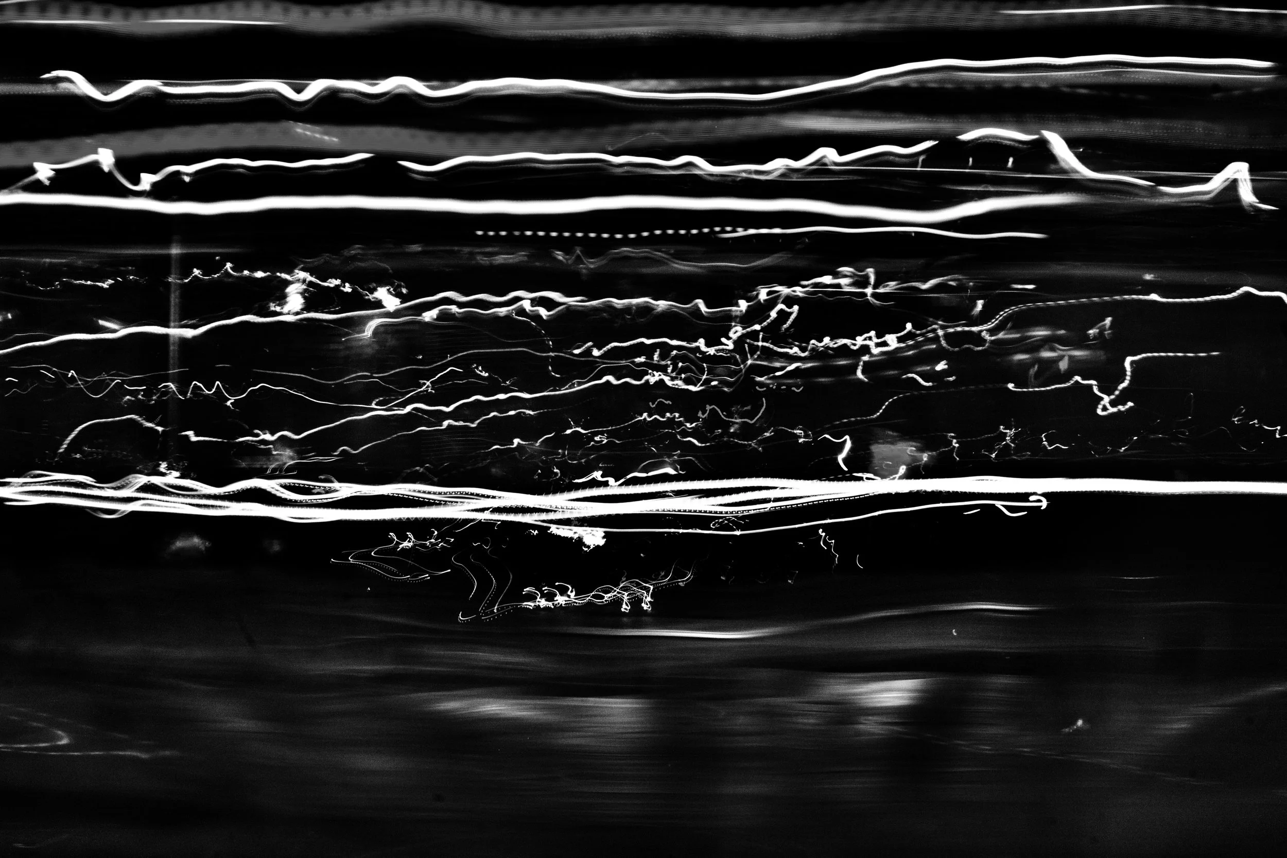 Abstract black and white photograph of light trails creating wavy and squiggly lines across the image.