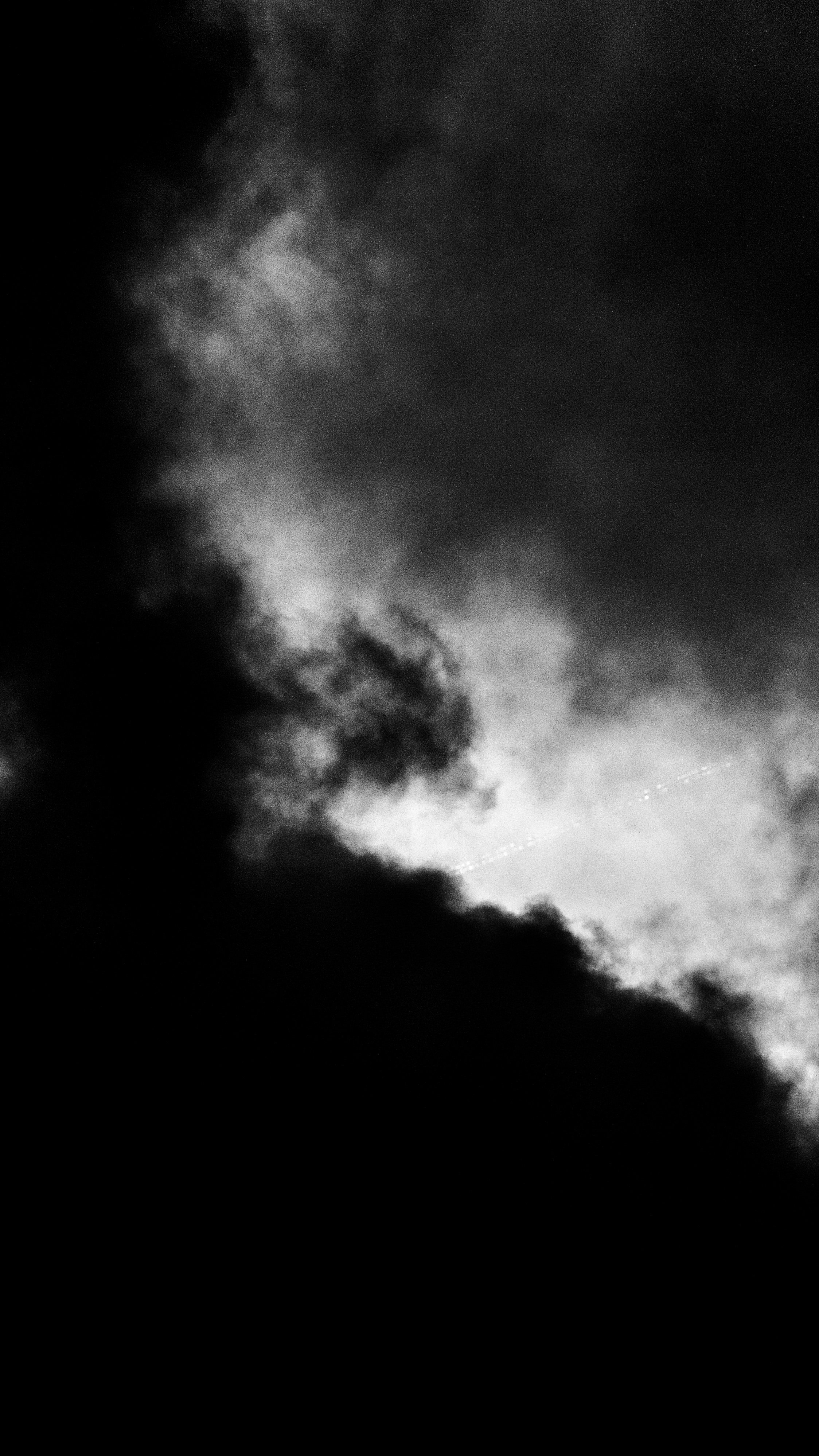 Dark storm clouds in a black and white photo with a small section of light at the bottom right corner.