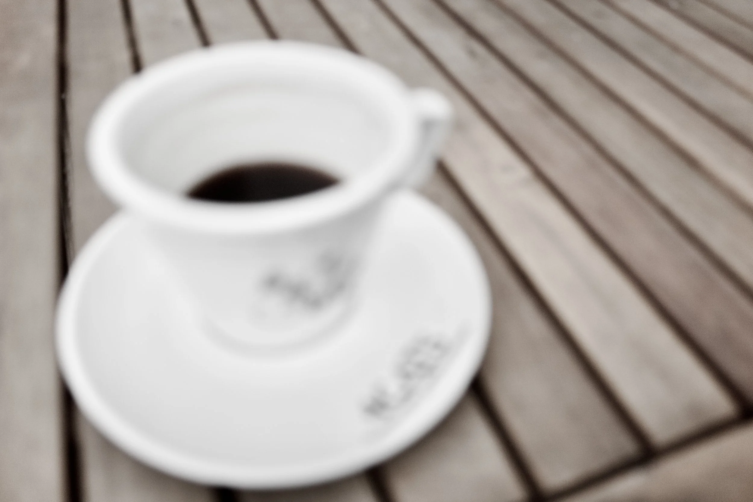 A white mug filled with black coffee, placed on a wooden surface.