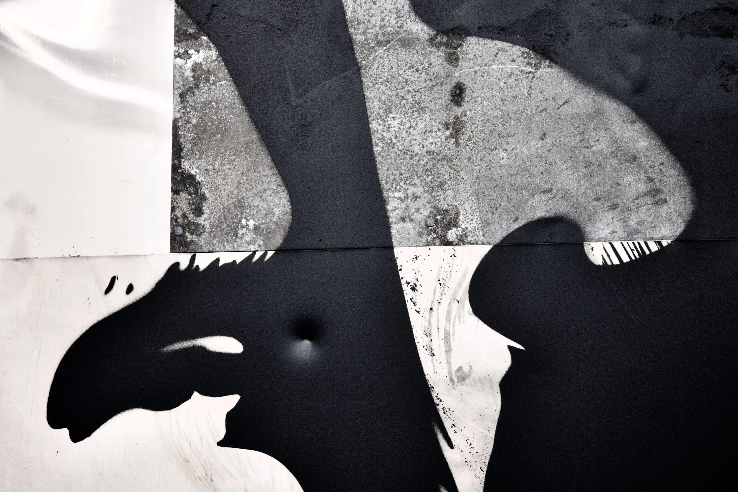Close-up of a stencil graffiti of a person's silhouette on a wall, with shadows cast across the surface.