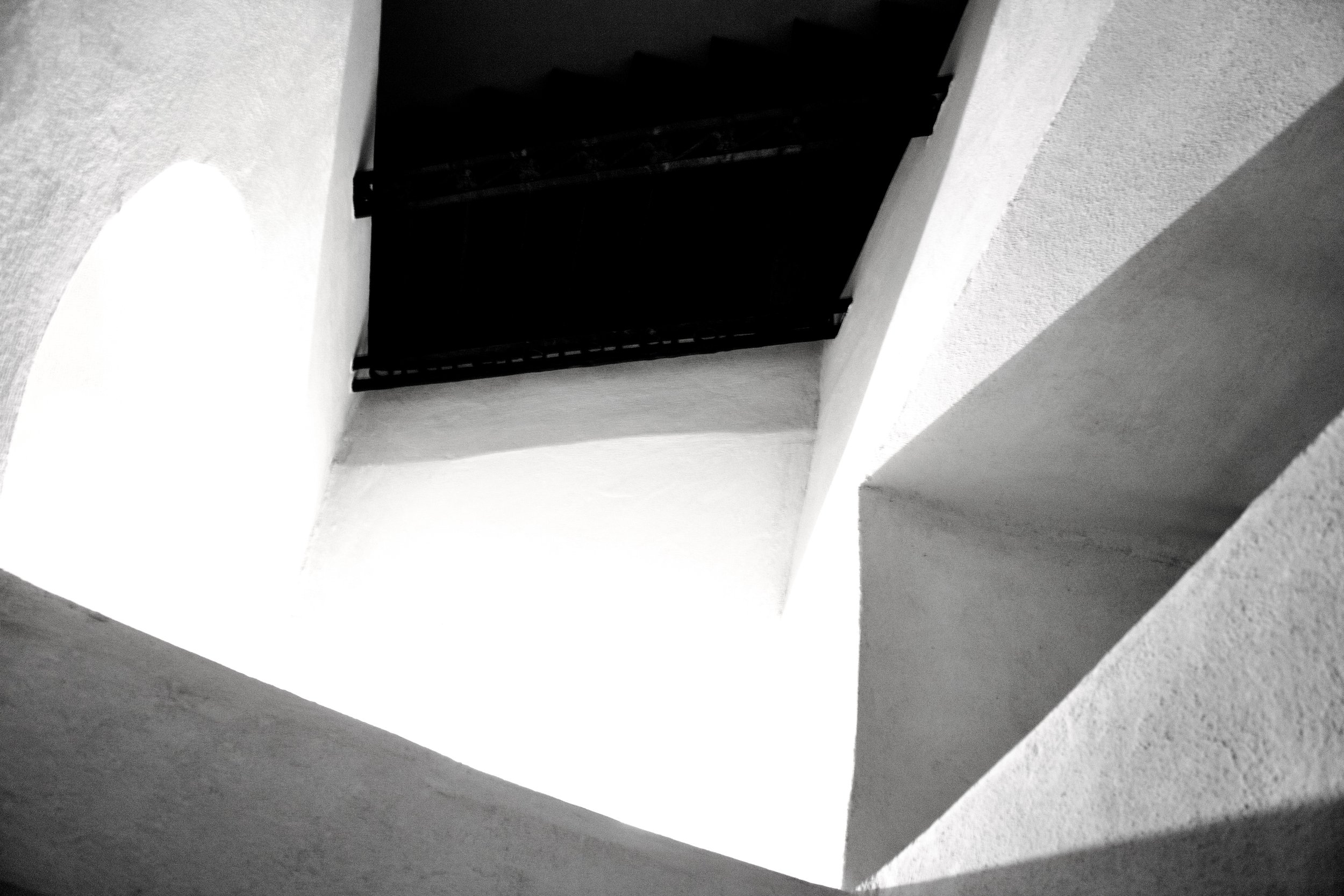 A dark opening or vent in a white textured ceiling or wall, with the photo taken at an angle.