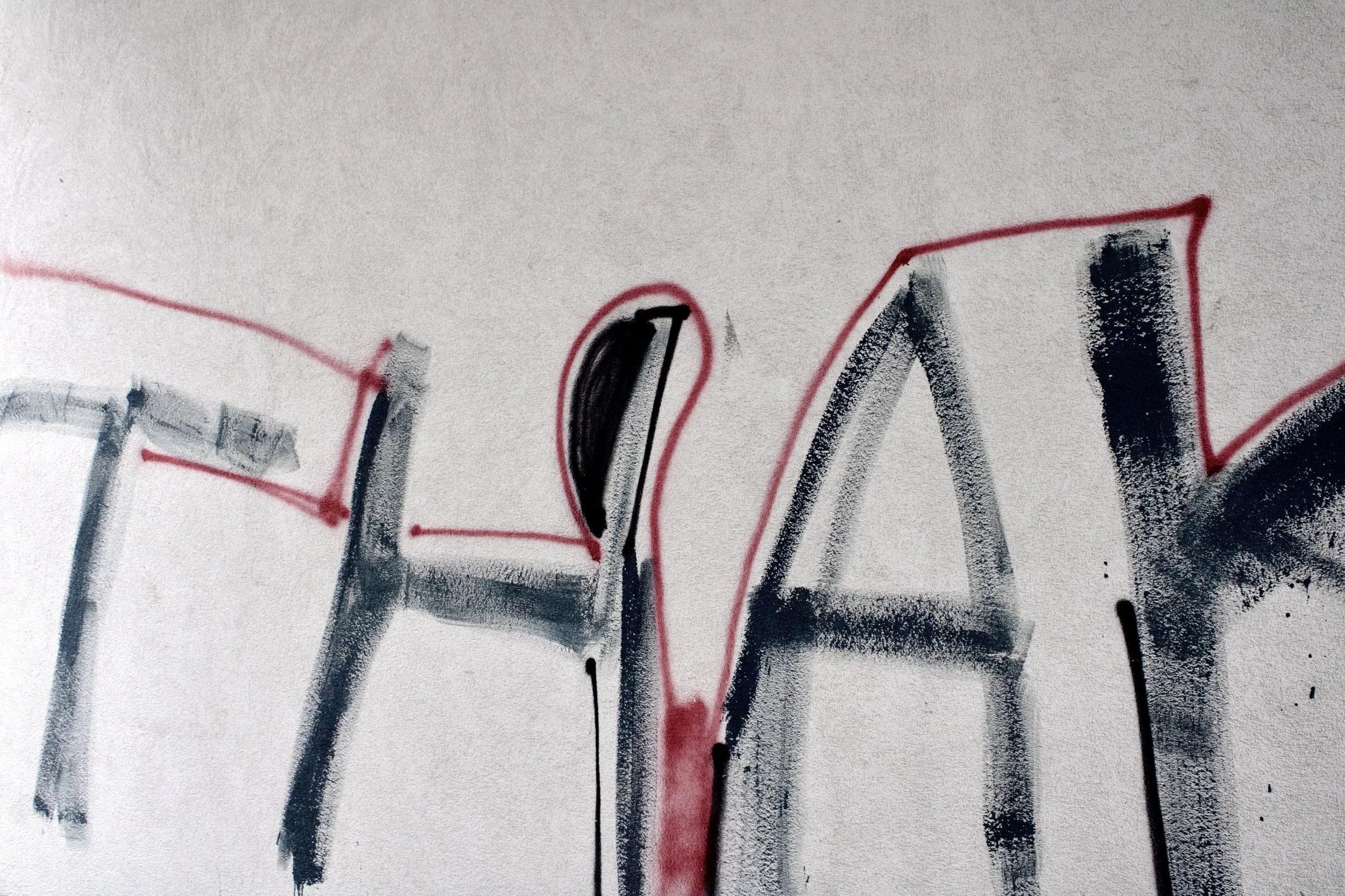 Close-up of spray-painted graffiti on a wall with black and red lines forming the word 'love'.