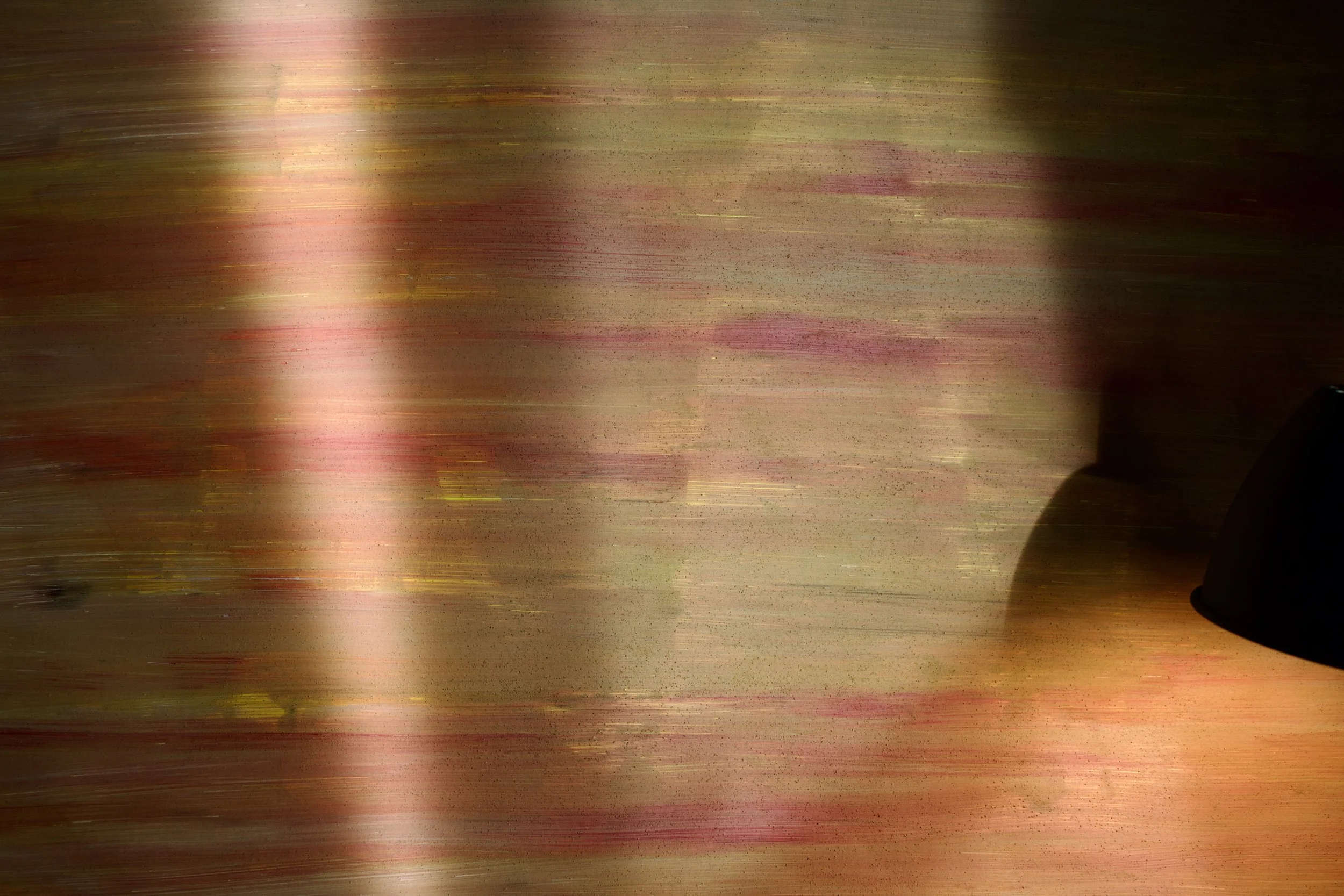 Blurred motion of pink, green, and brown streaks, with a black object at the bottom right corner.
