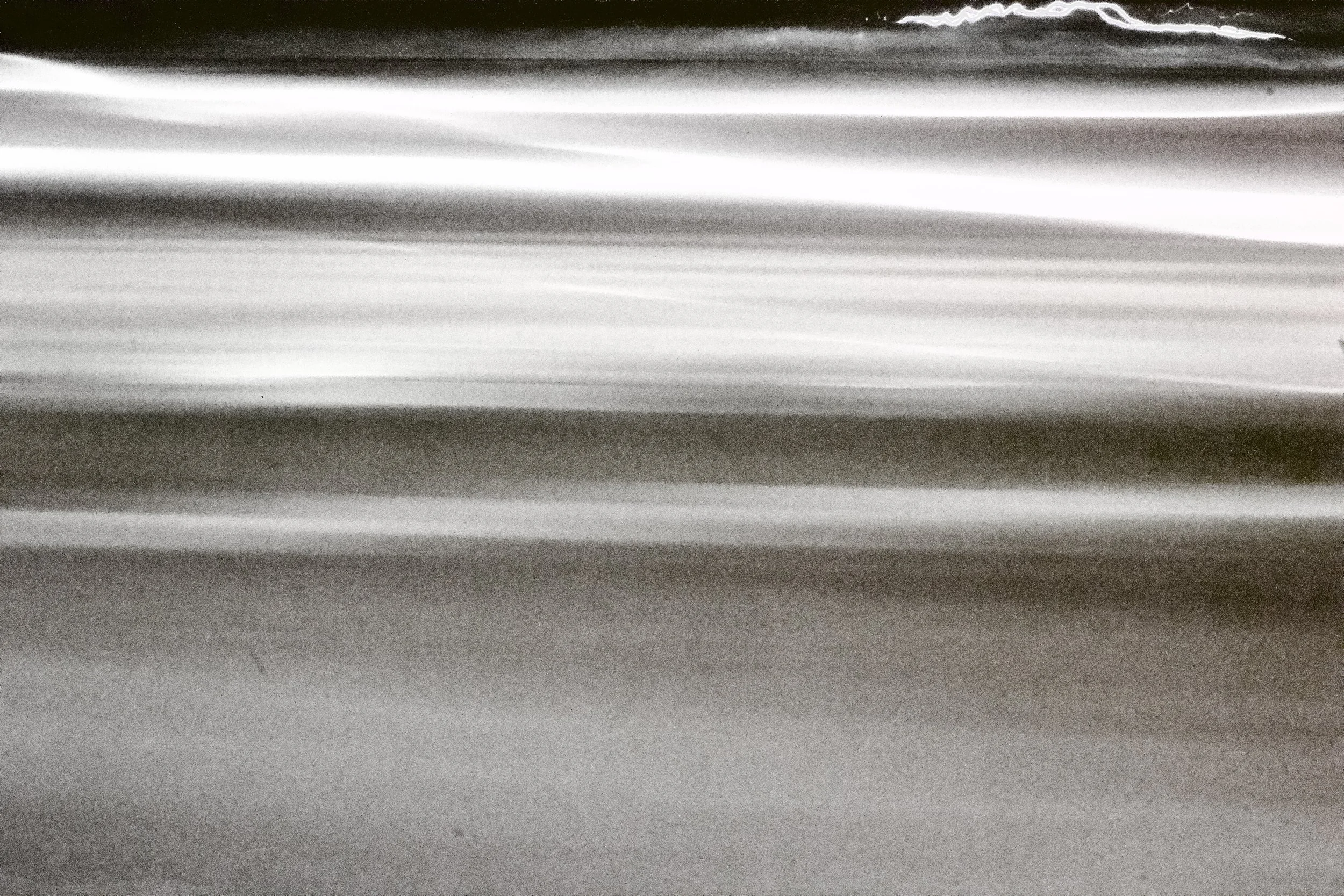 Close-up of a textured metallic surface with horizontal lines and varying shades of gray and silver.