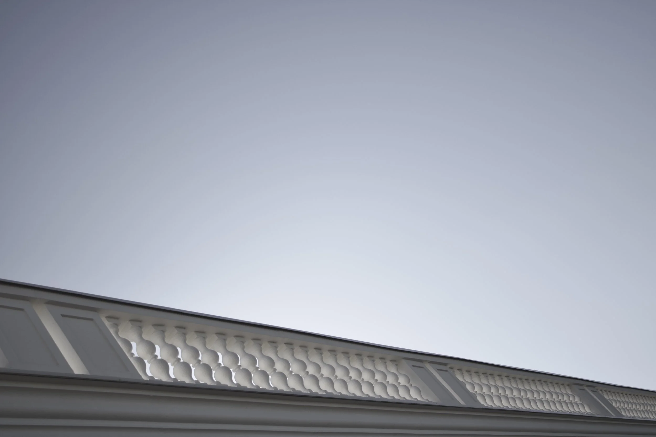 View of house roof with decorative trim against a light blue sky.