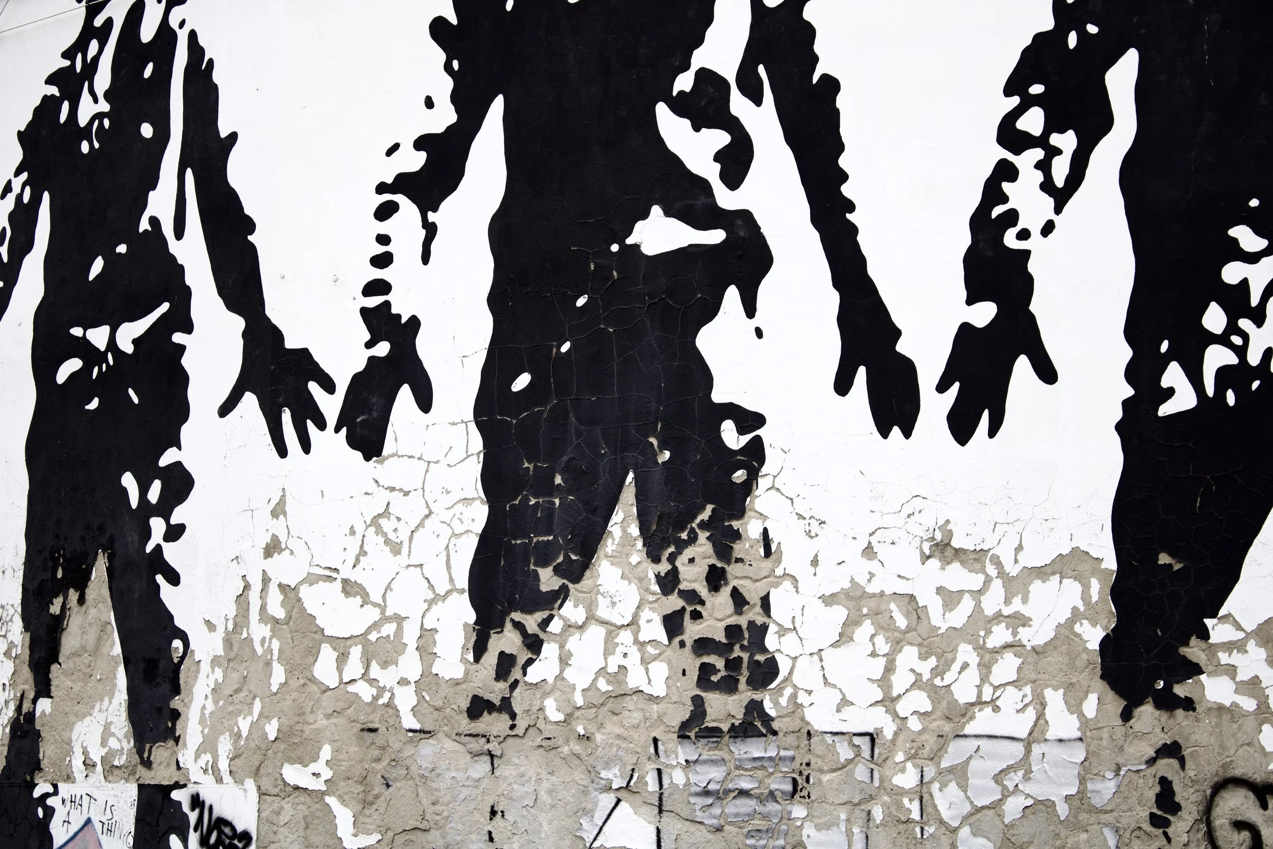 Black silhouette of two people on a wall with cracked peeling paint.