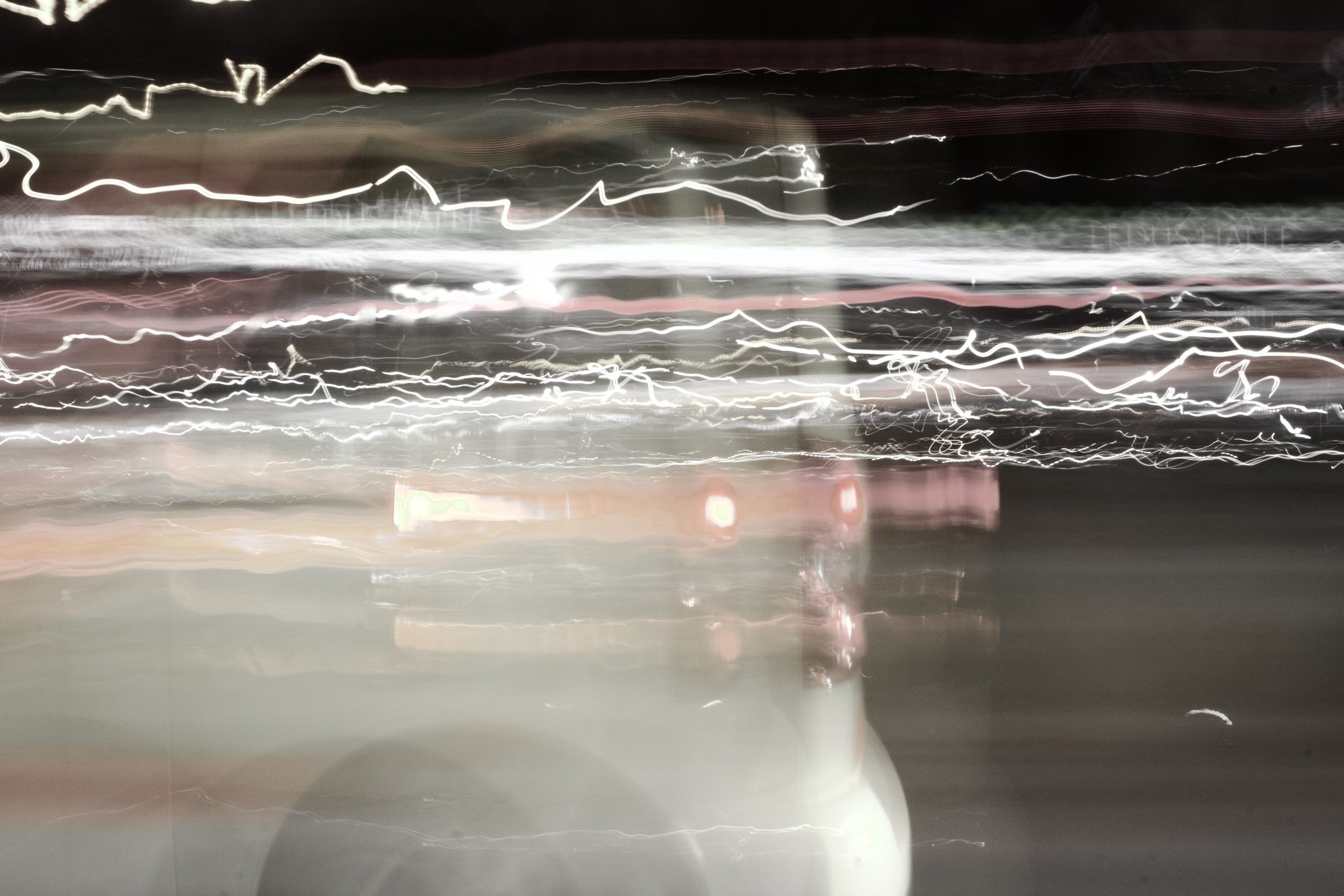 Blurred image of city lights at night with streaks of light from moving vehicles.