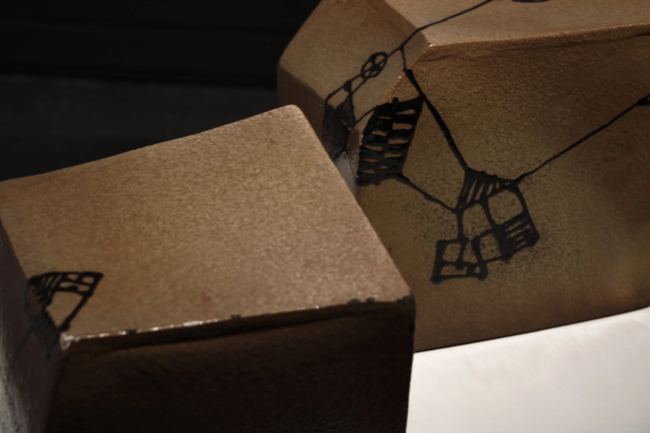Close-up photo of cardboard boxes with black printed wine bottle illustrations on brown textured surface.