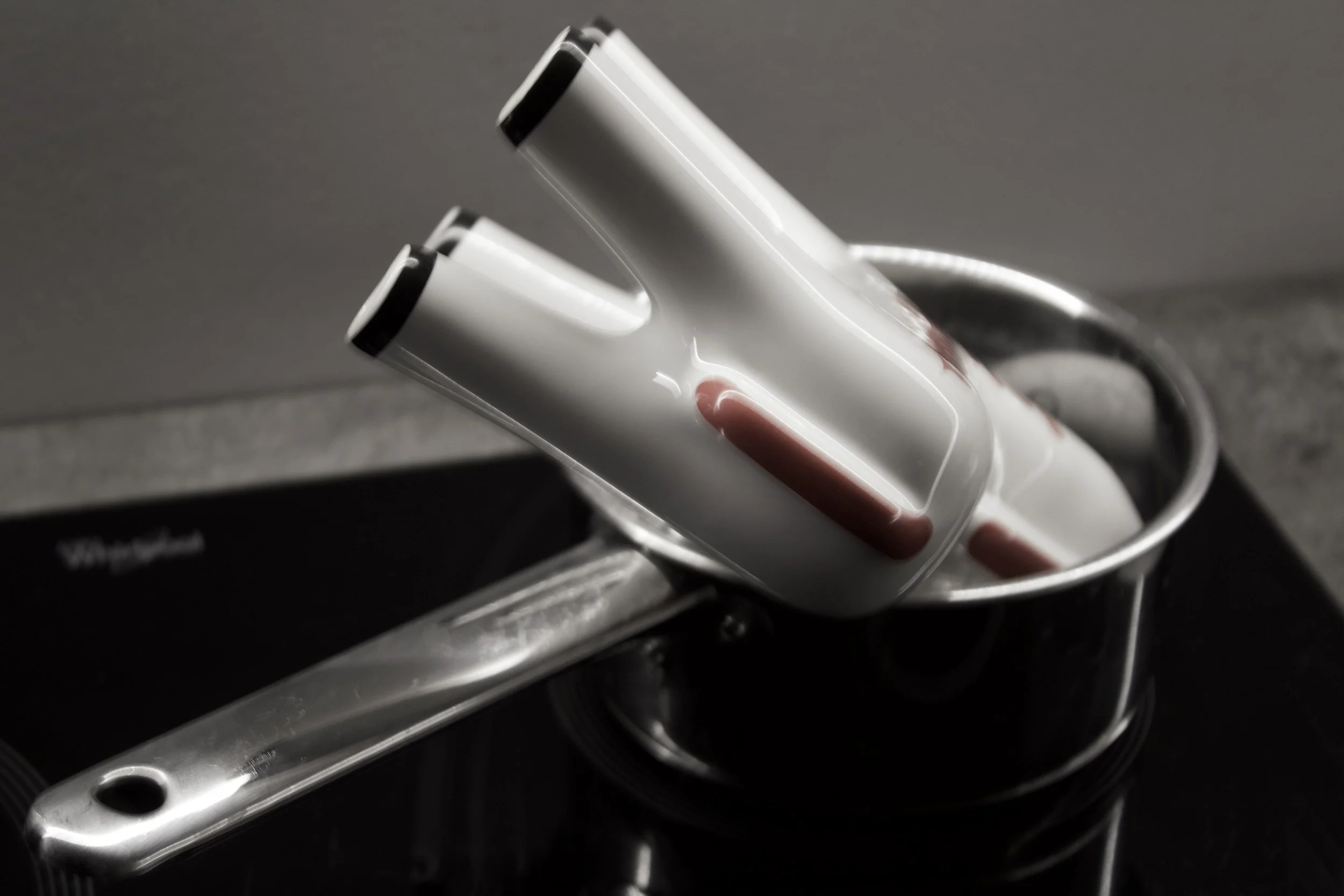 Multi-directional curling iron with a white body and black accents, resting on a metallic surface.