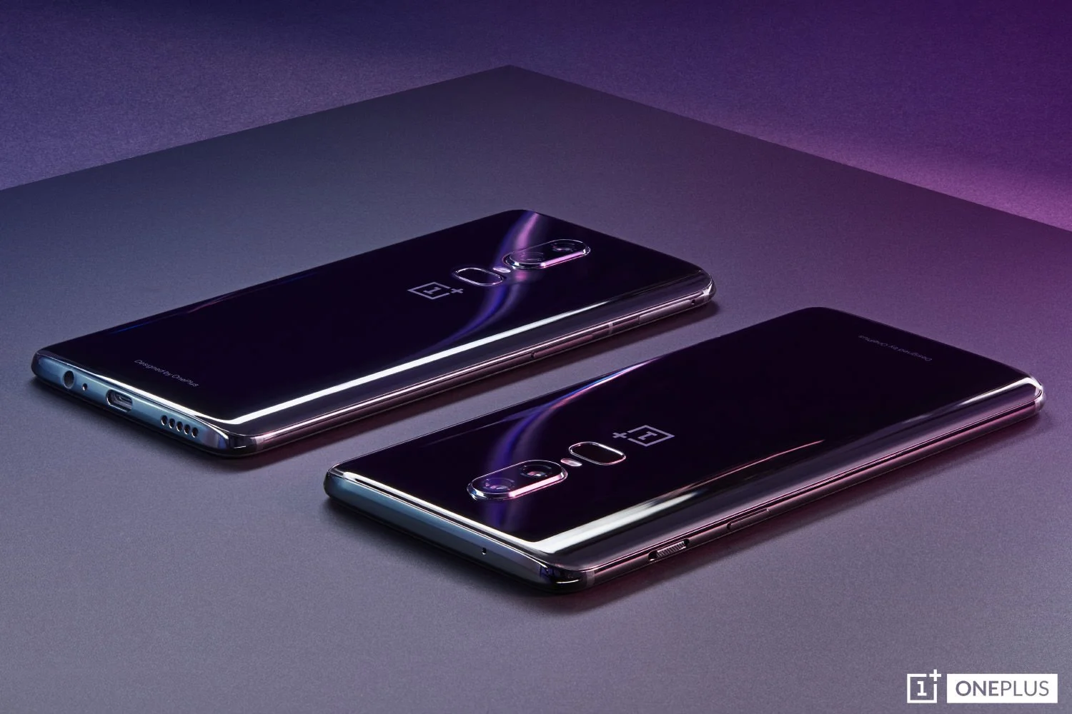 Two OnePlus 6 smartphones with glossy reflective backs lying face down under dramatic purple and blue studio lighting.