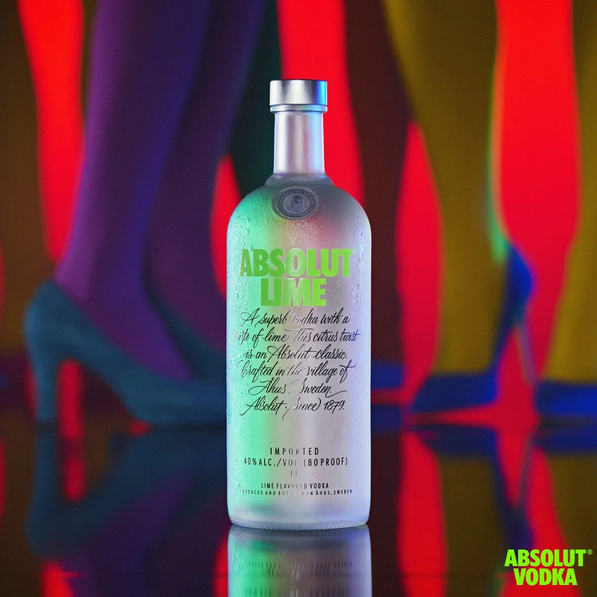 Frosted bottle of Absolut Lime vodka against a vibrant background of colourful silhouettes and high heels.