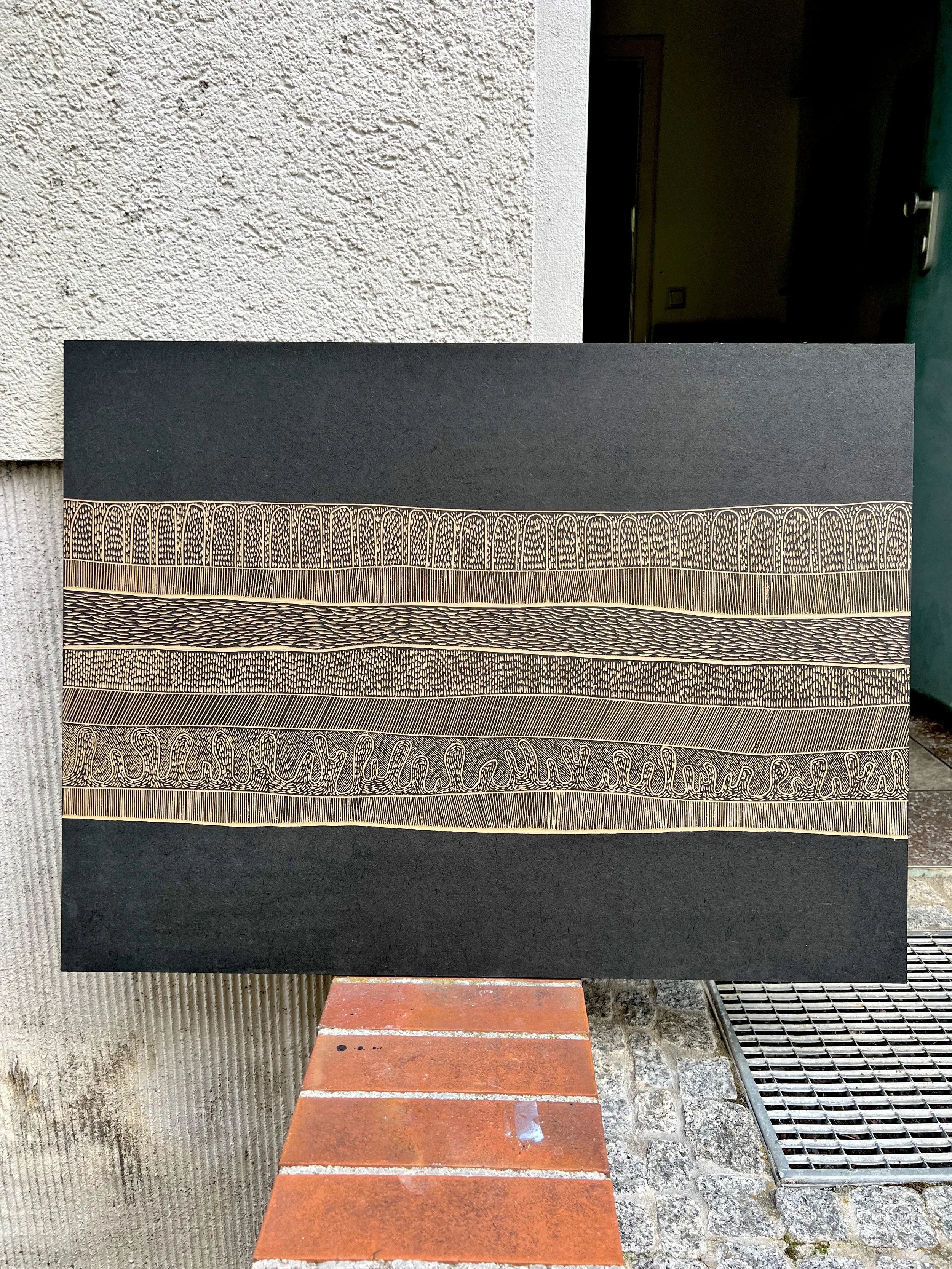 Abstract artwork with intricate patterns on a black background displayed against a textured wall, featuring various lines and curves.