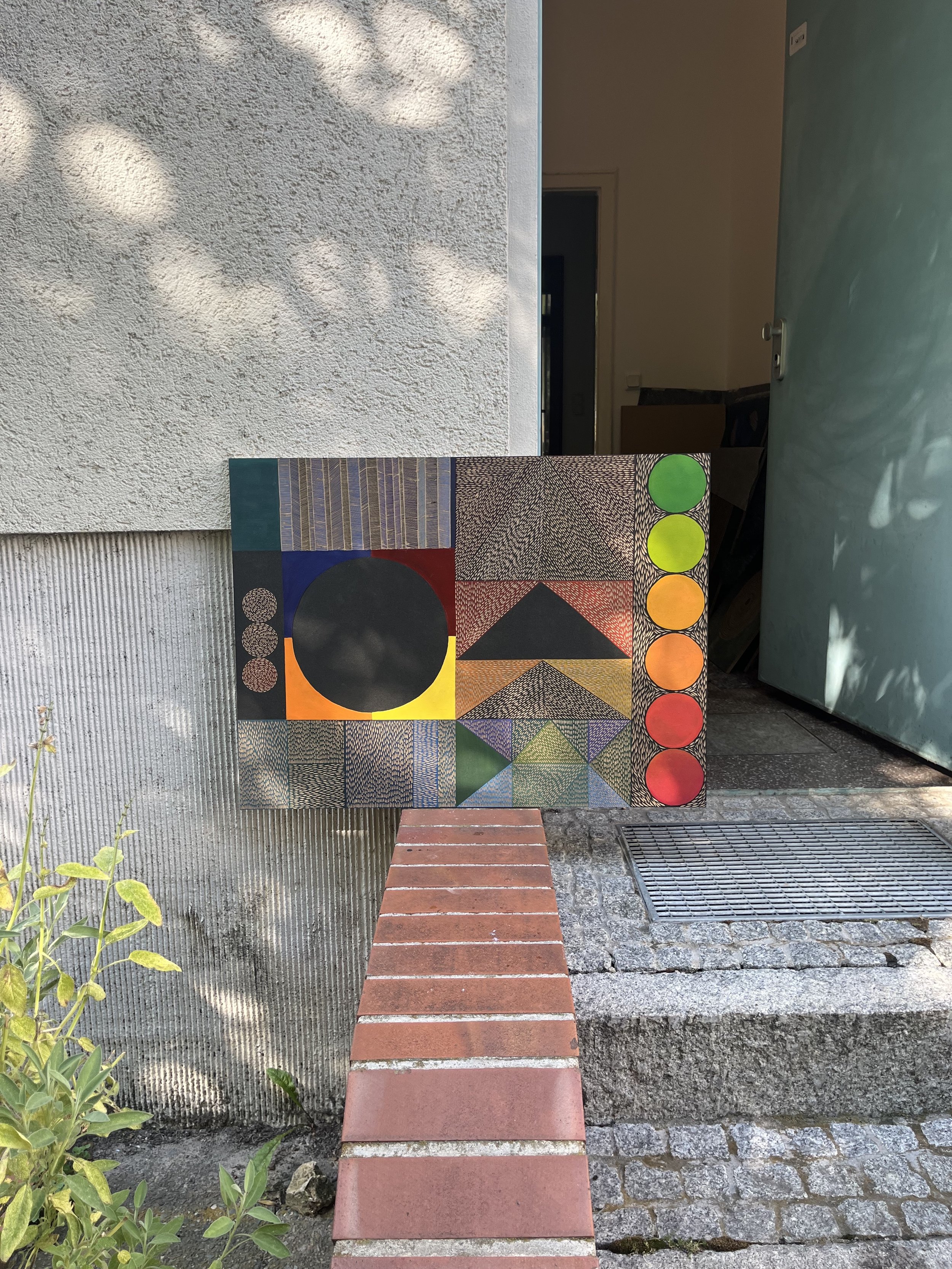 Abstract artwork with geometric patterns and vivid colors placed outside a building entrance.