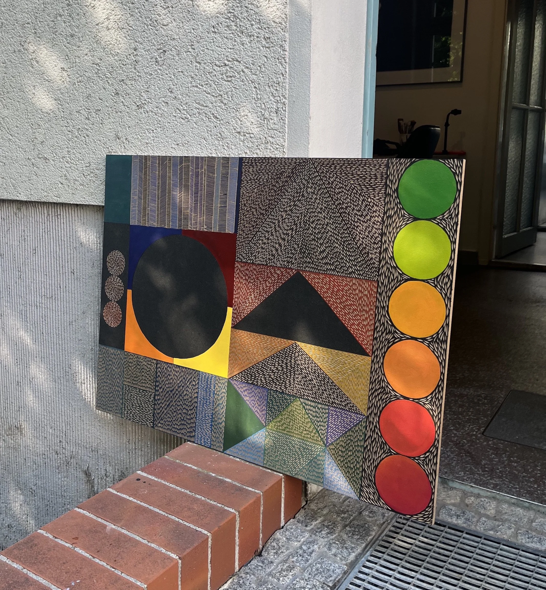 Abstract geometric artwork with circles, triangles, and various patterns displayed outdoors.