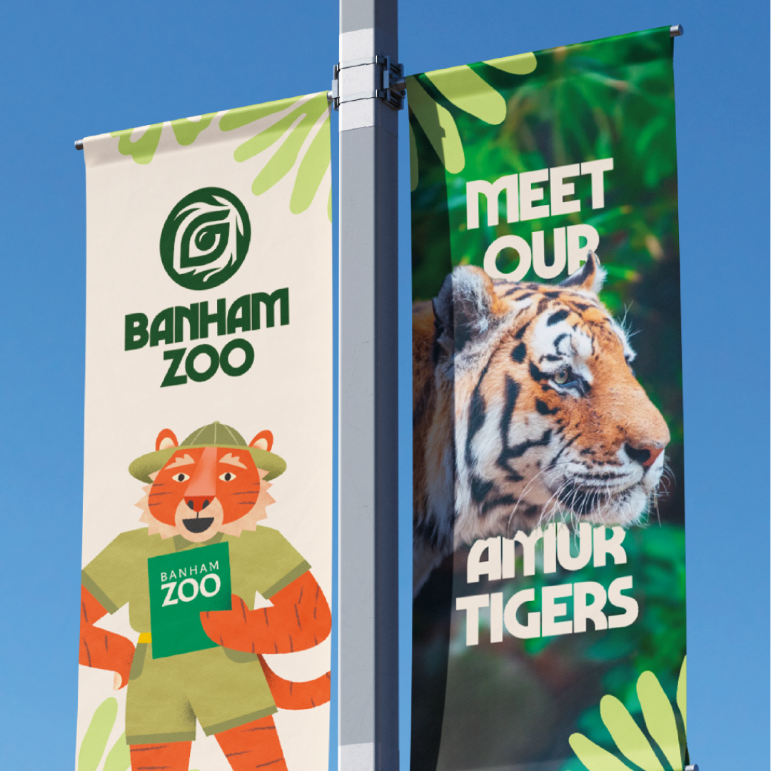 Colorful banners promoting Banham Zoo, featuring a cartoon tiger mascot and a real tiger with text 'Meet Our Amur Tigers' against a blue sky.