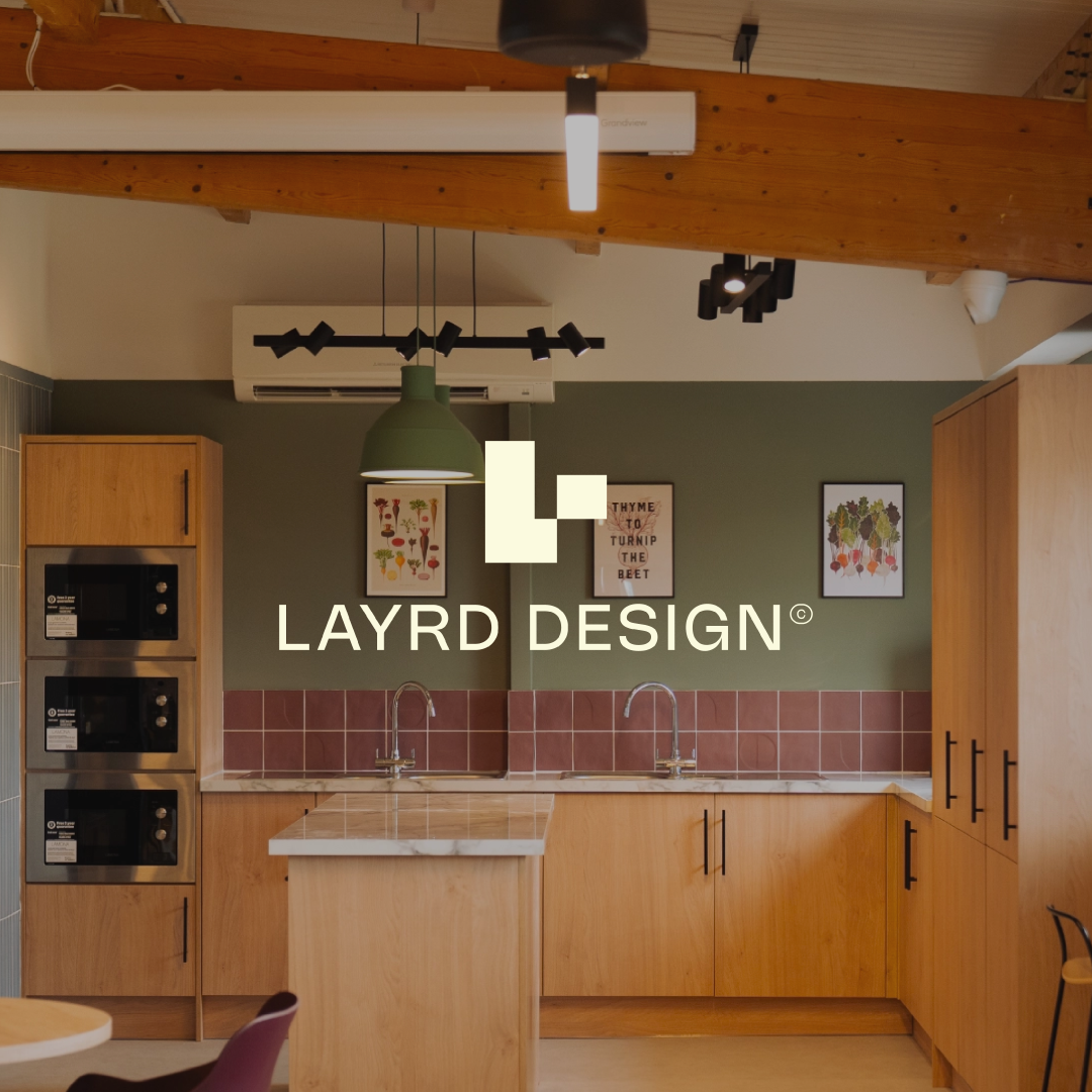 Modern kitchen with wooden cabinets, pink tile backsplash, double sink, and various framed botanical prints on olive green wall.