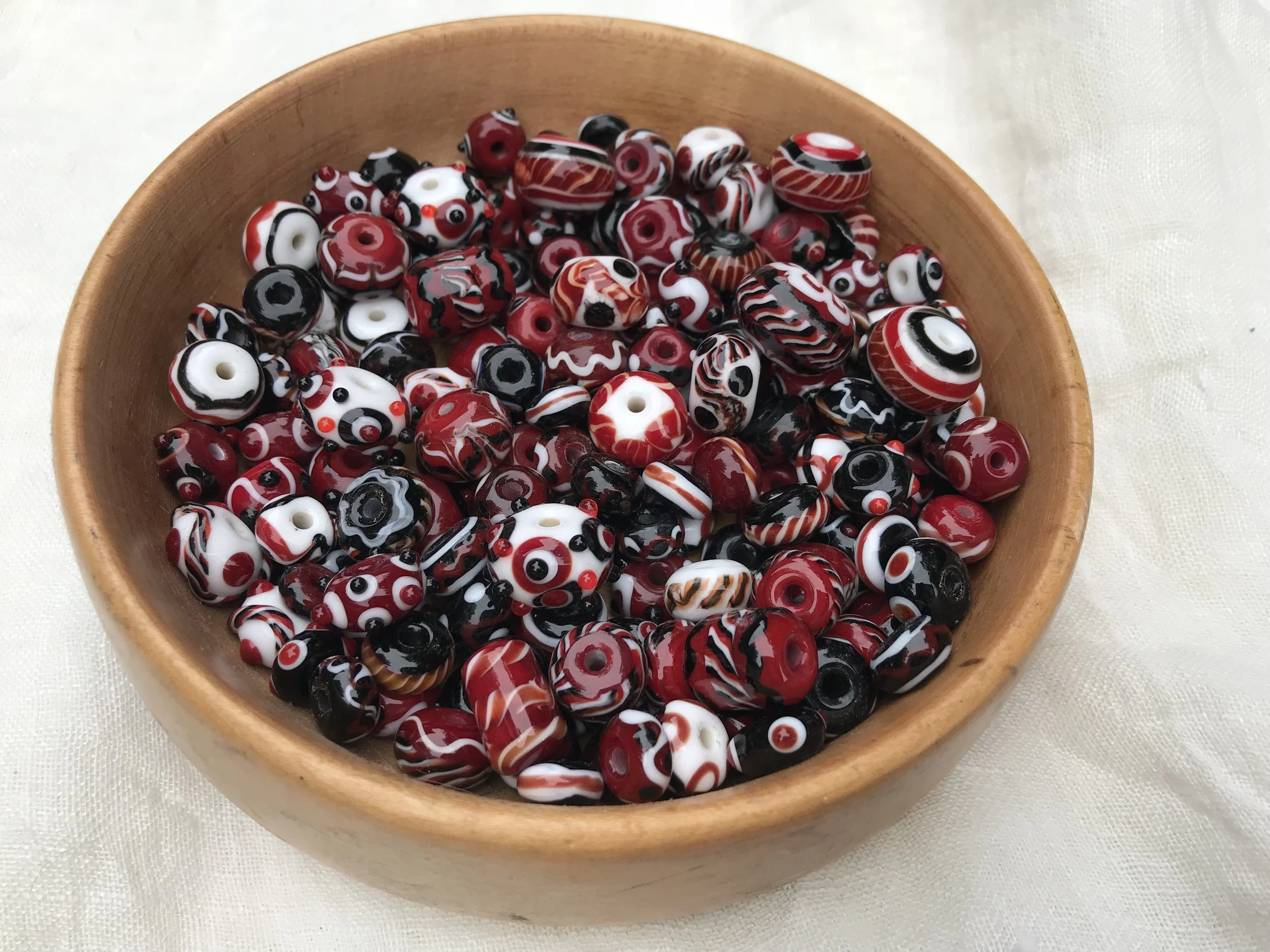 Wooden bowl filled with red, black, and white beads