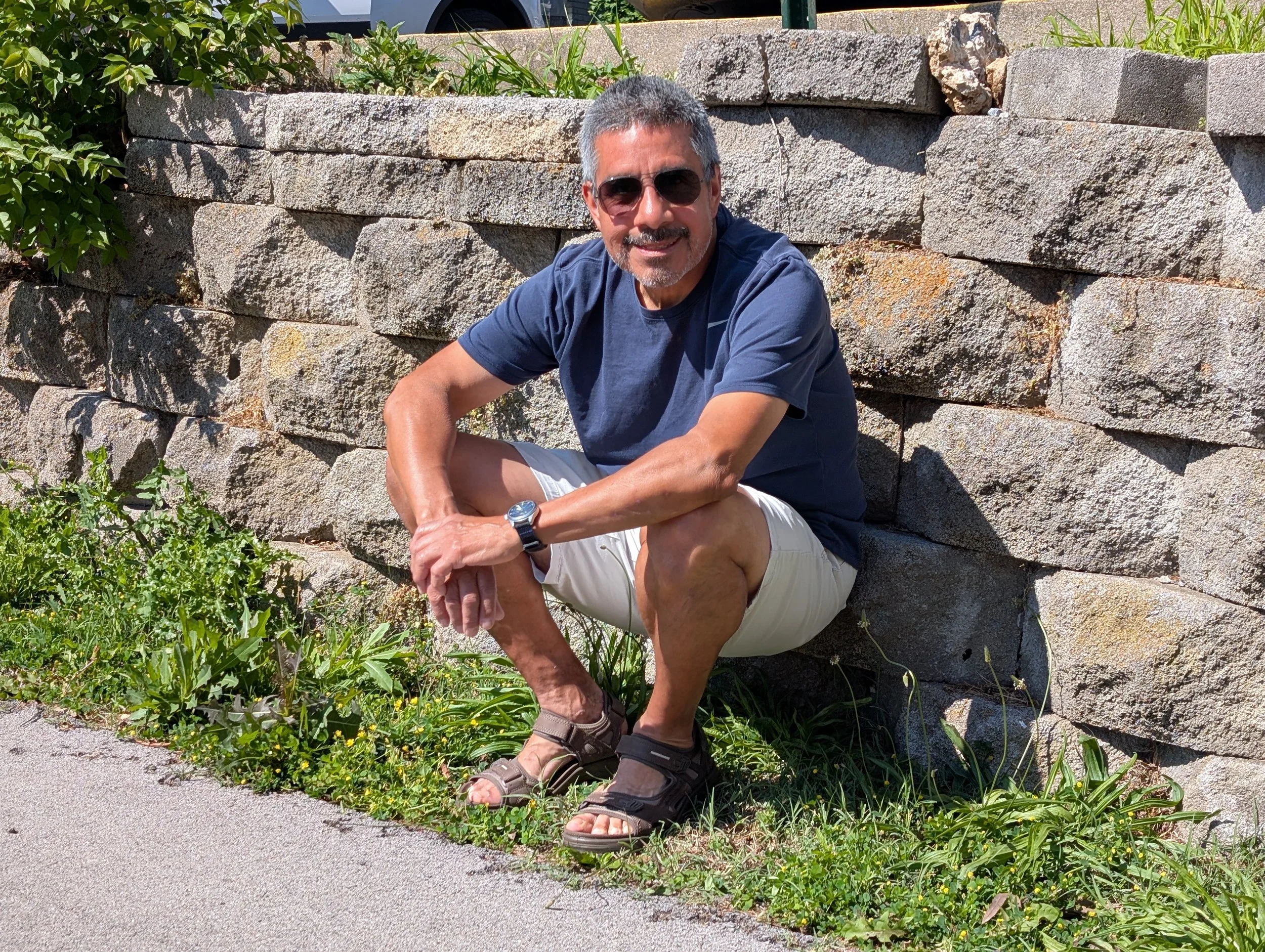 man sitting by stone fence wearing Ecco Offroad sandals